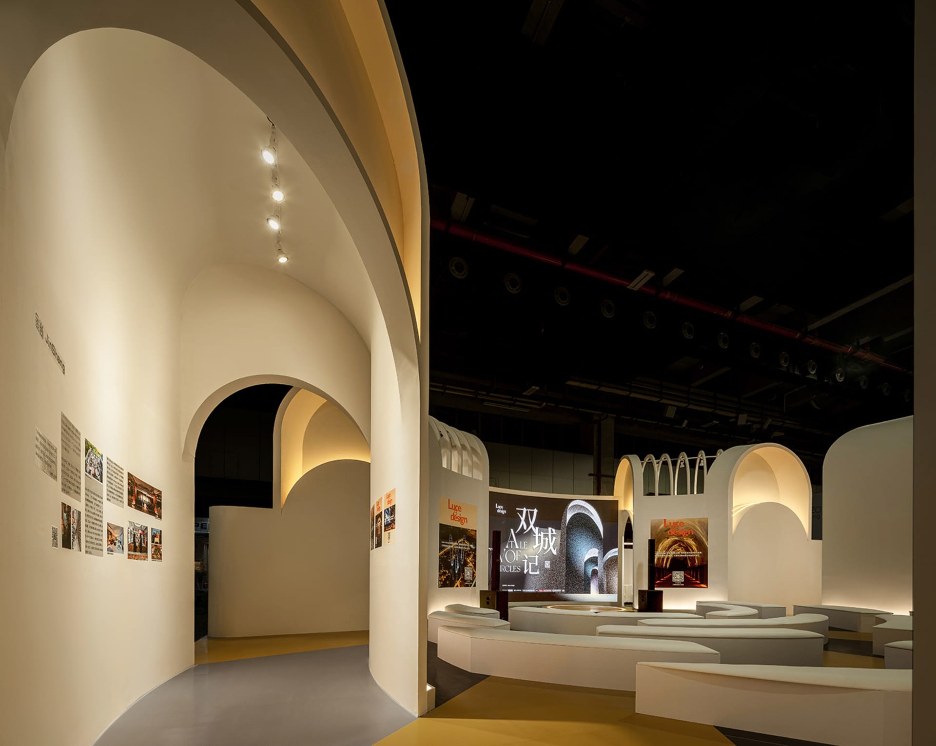 Industrial exhibition space featuring a white concrete design with curved arches and illuminated interiors.