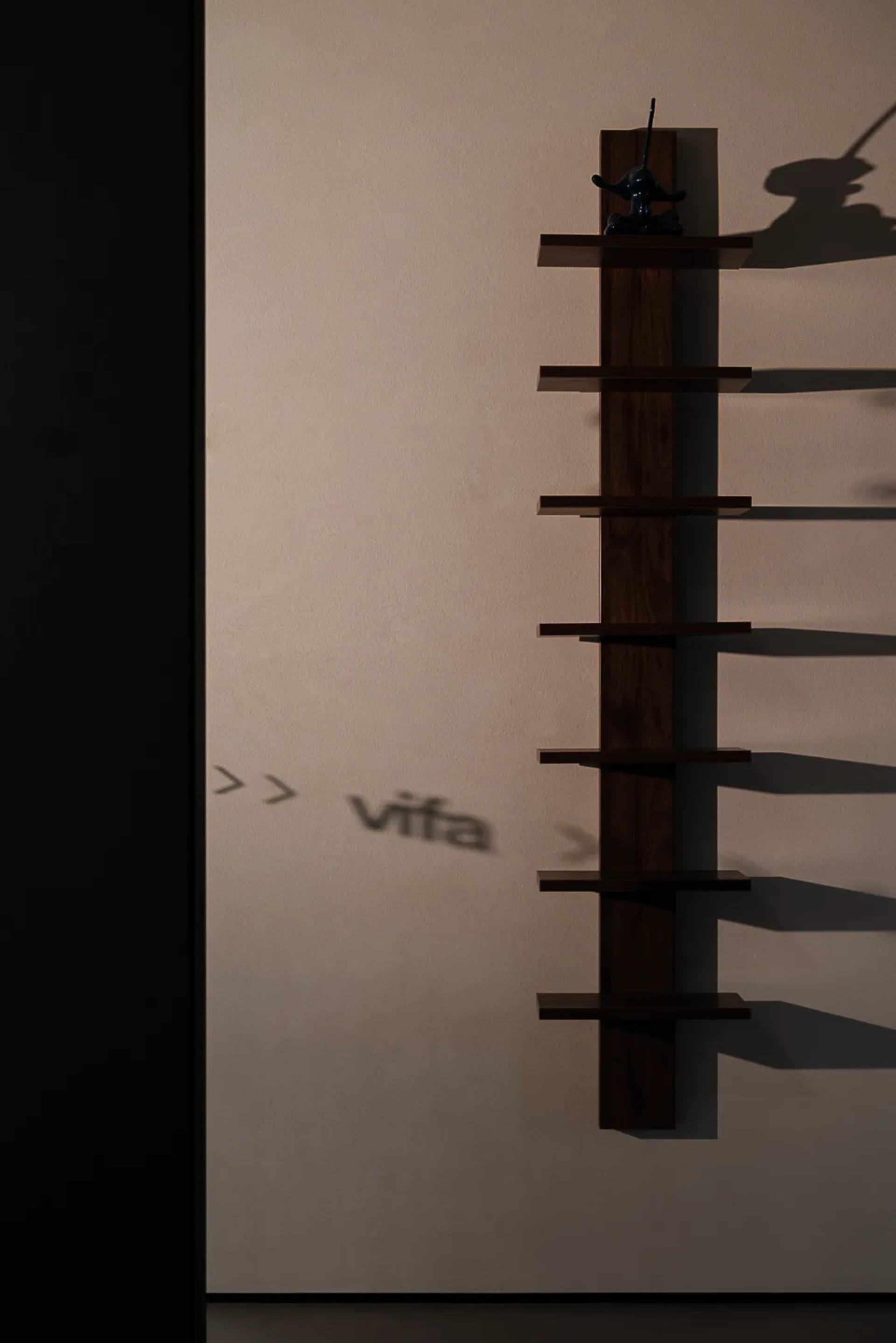 A modern wooden shelf mounted on a wall with shadows reflecting on it.