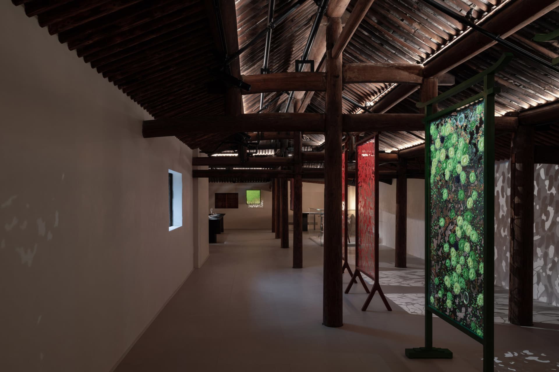 工業風格的展覽空間，展示布料包覆的柱子與精緻的綠色圖案。