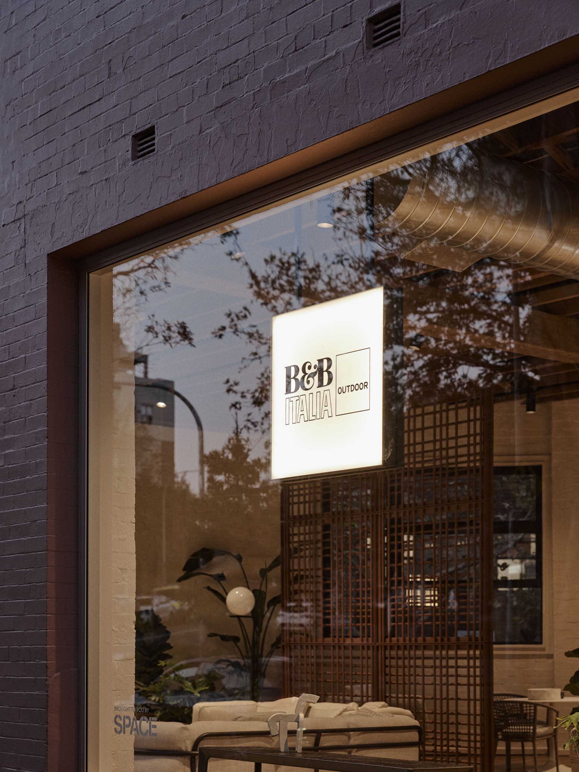 A modern storefront with a glass facade featuring botanical elements.