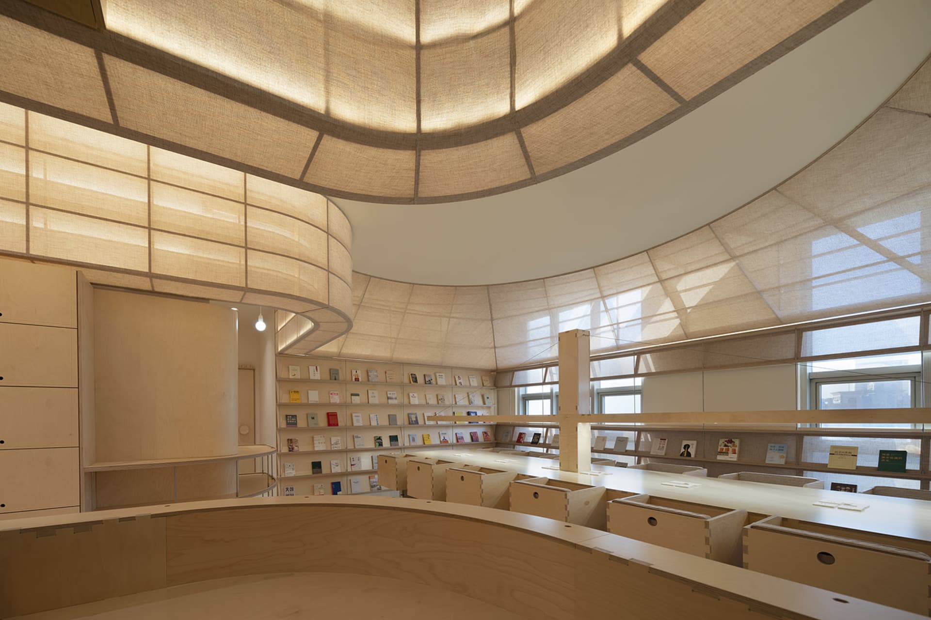 A modern library interior with wooden shelves and a curved ceiling.