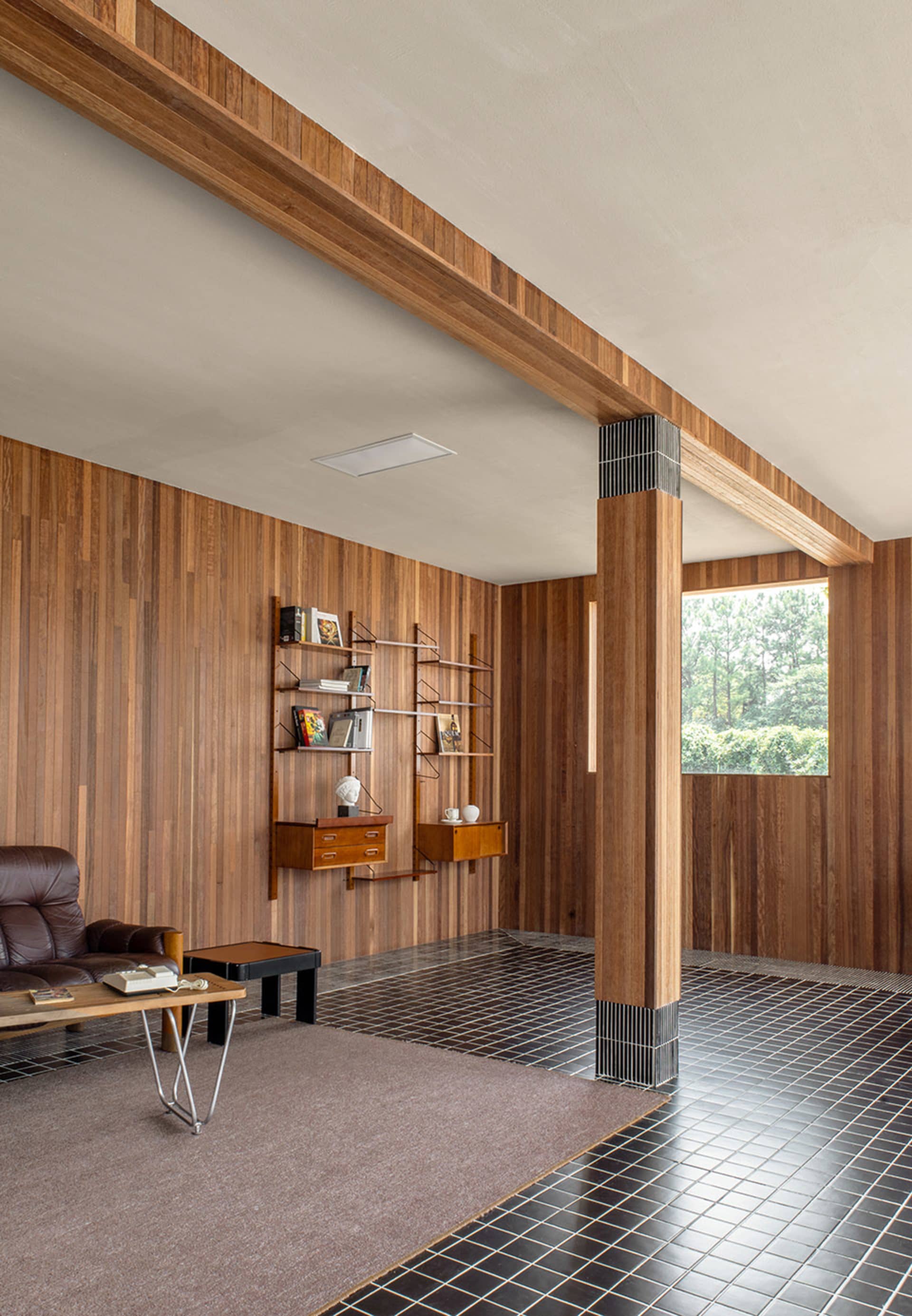 A modern living room with wooden walls, black and white tiled flooring, and a mix of furniture and decor items.