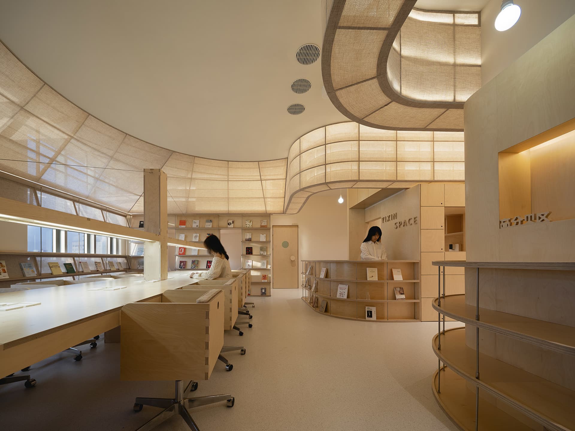 Interior of a modern library with curved wooden shelves and a minimalist design.