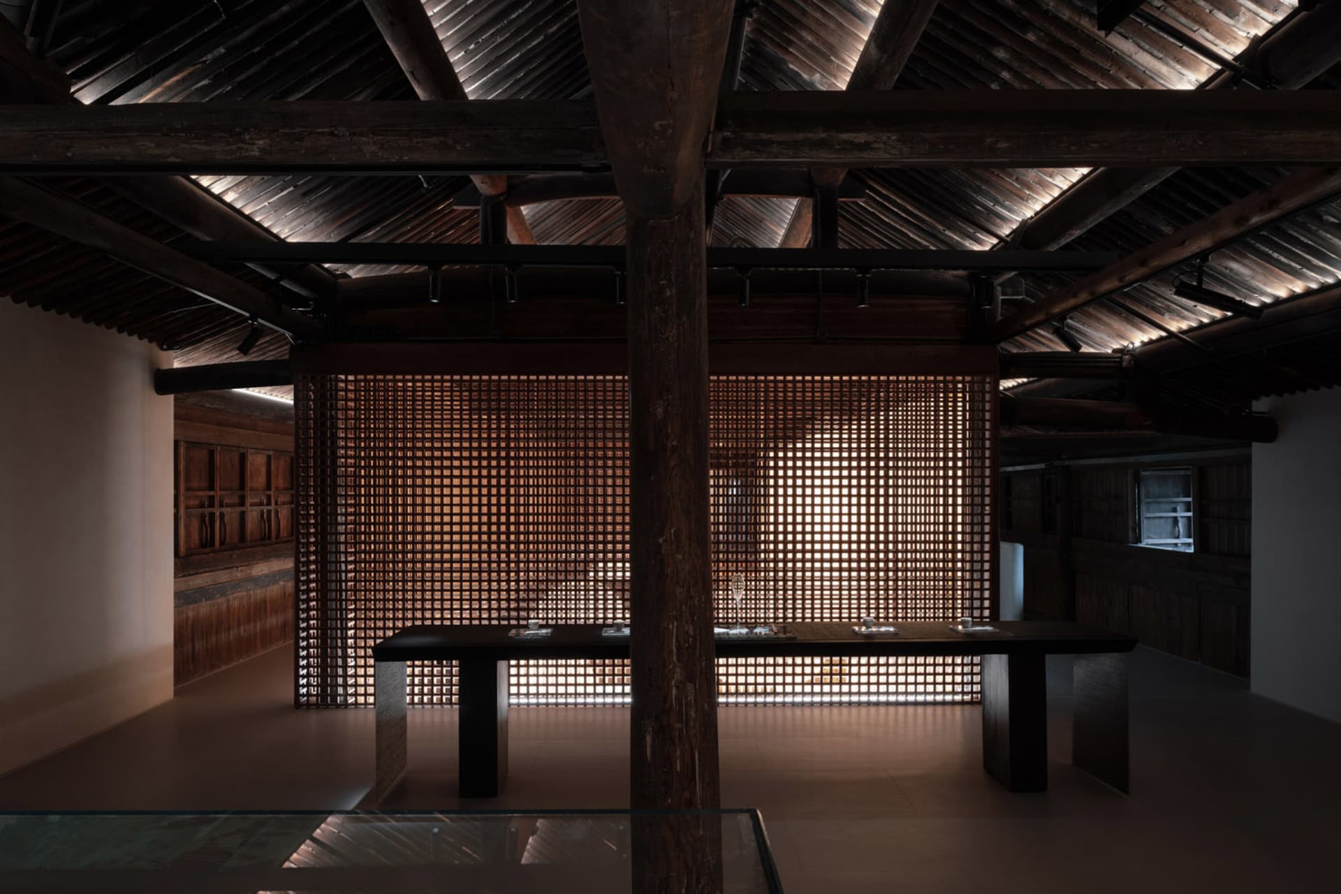 A traditional woven wall interior featuring wooden beams and a glass-topped table with items on it.