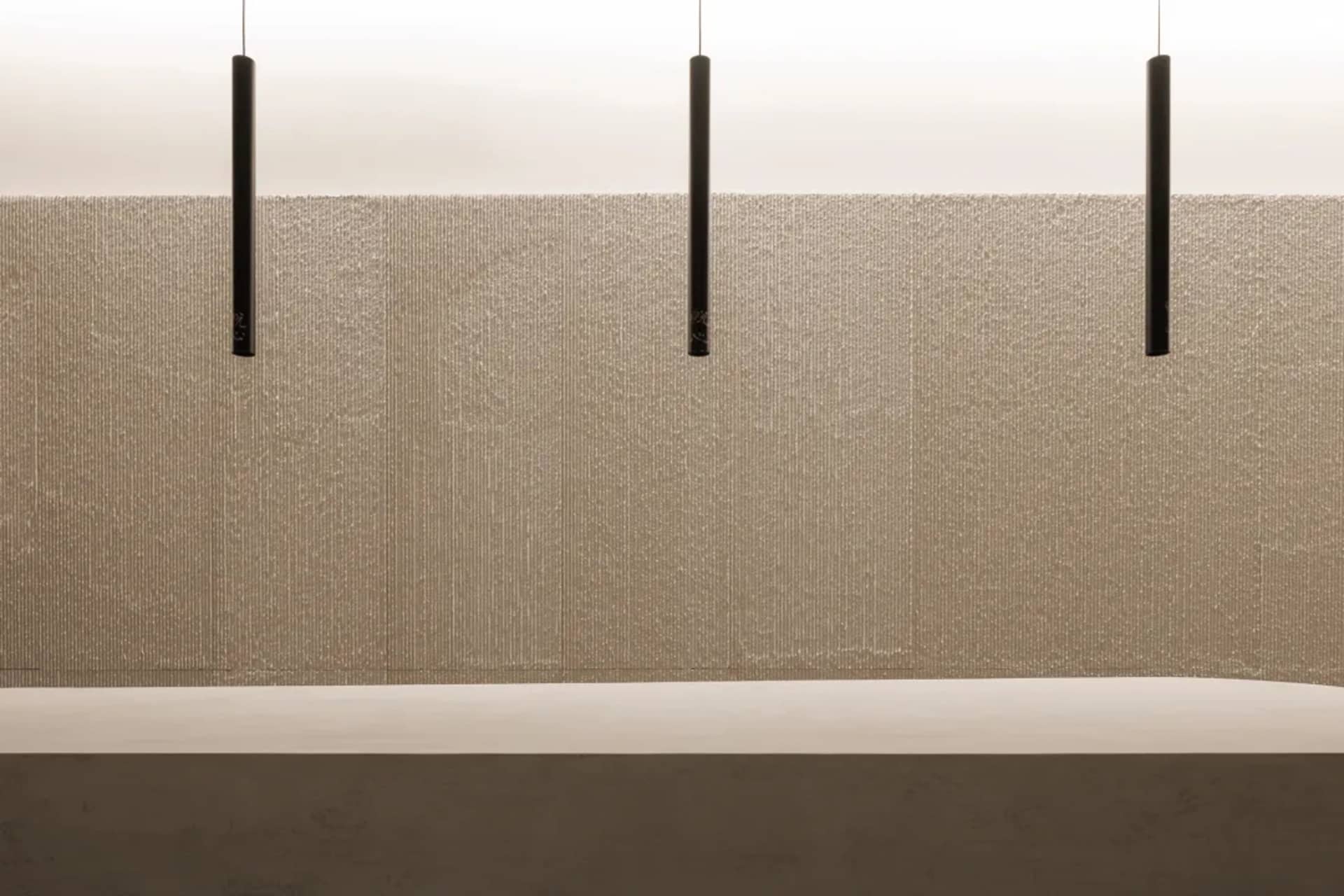 A minimalist interior space featuring a textured wall and sleek, modern lighting fixtures.