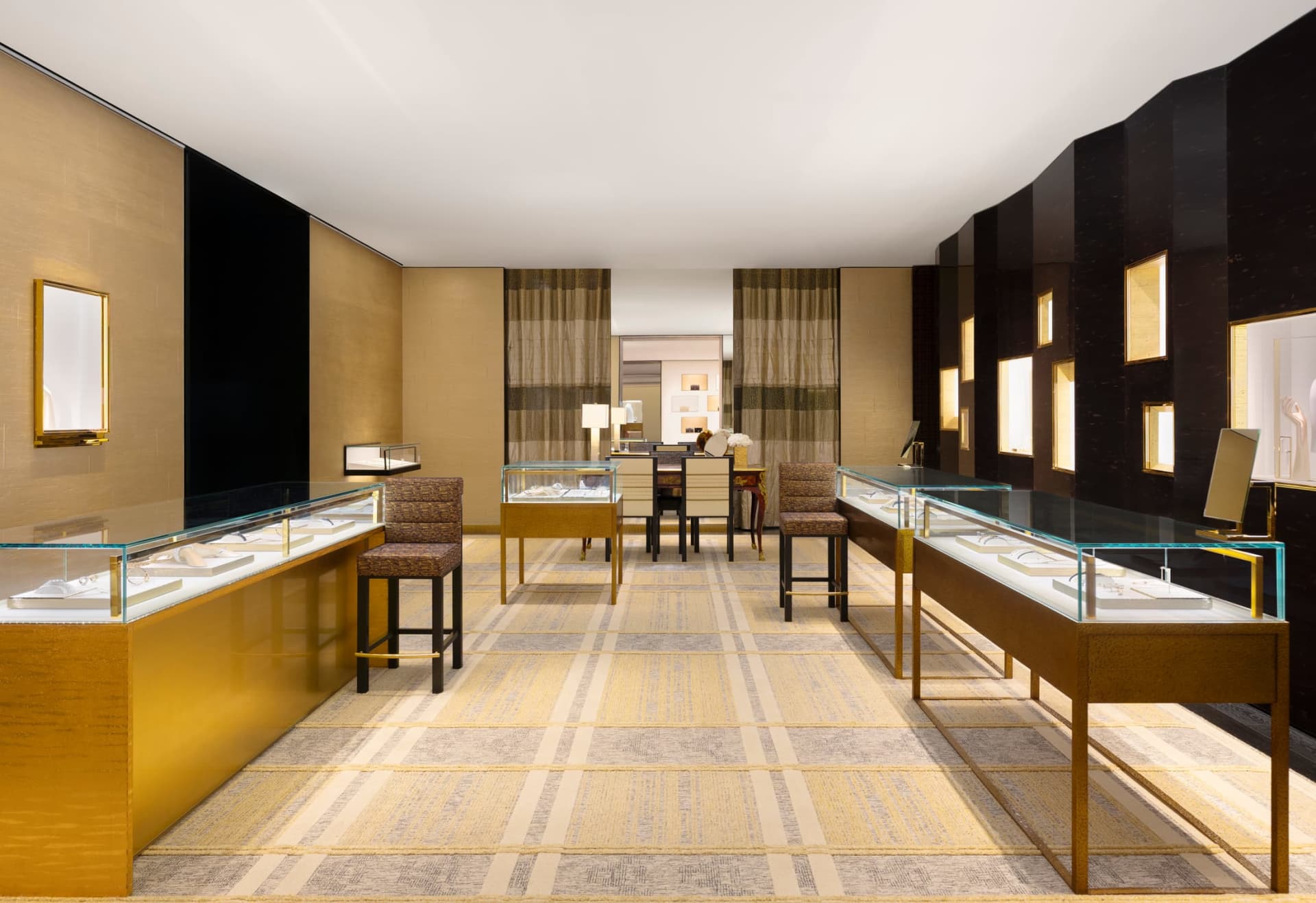A sophisticated retail jewelry shop featuring gold walls, glass display cases, and wooden furniture.