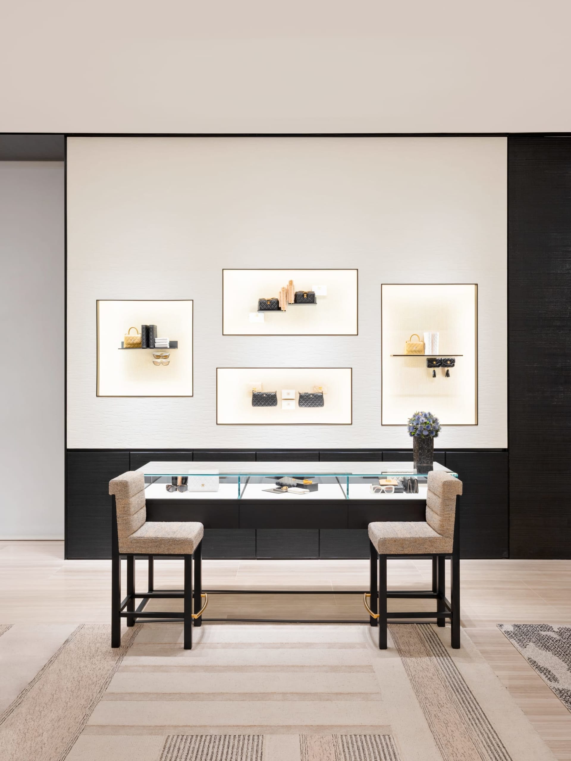 A modern retail display featuring a glass counter with various items on display, set against a polished concrete wall and sup