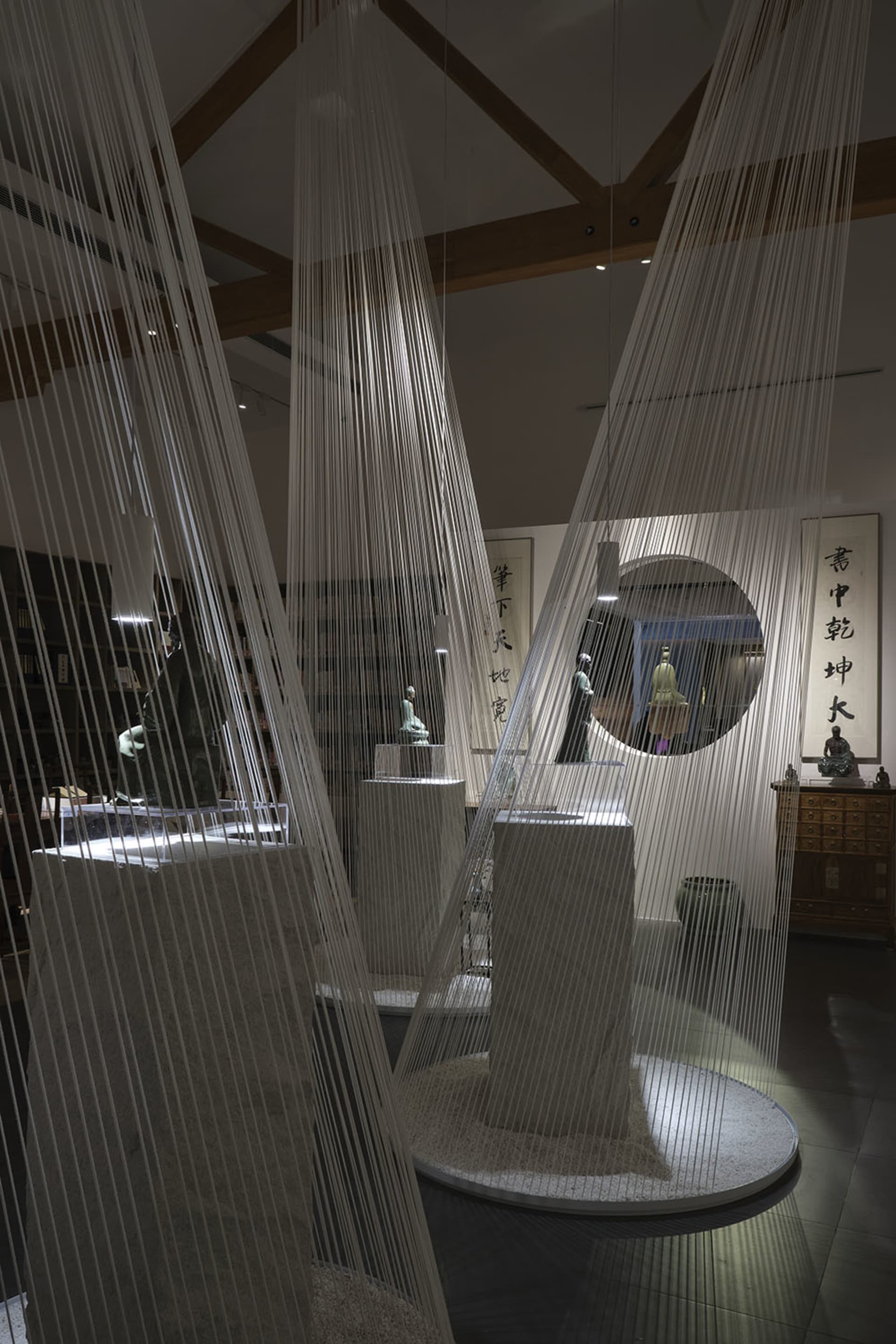 A contemporary museum exhibit featuring hanging fabric textile installations and sculptures.