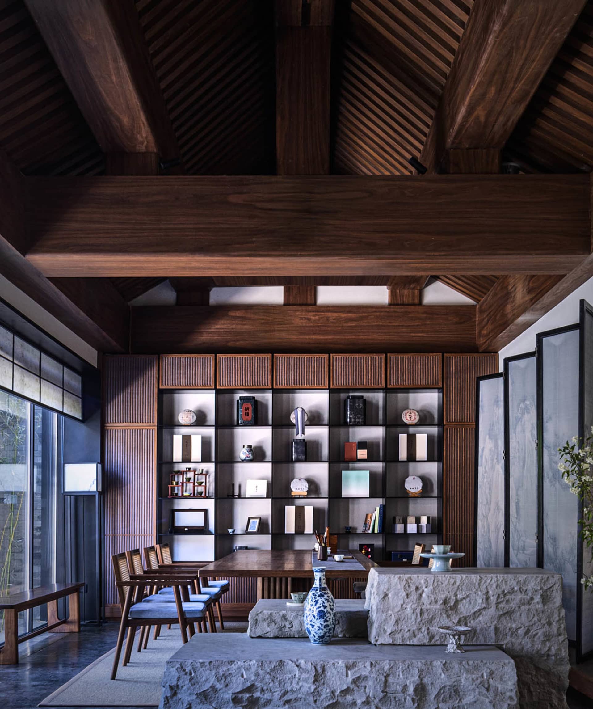 A modern living room featuring wooden furniture, stone elements, and glass windows.