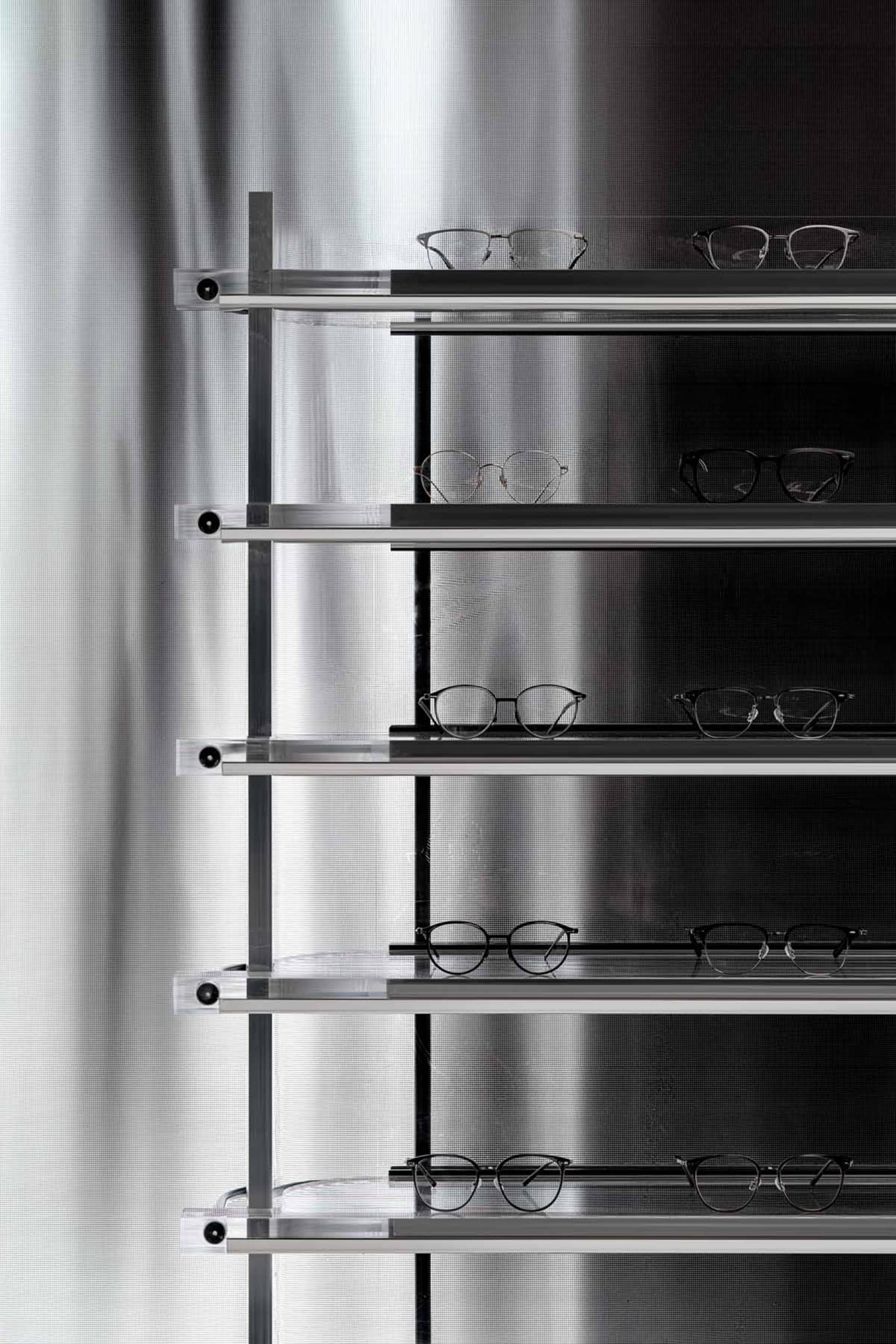 Metal shelves holding glasses in a modern optical shop.