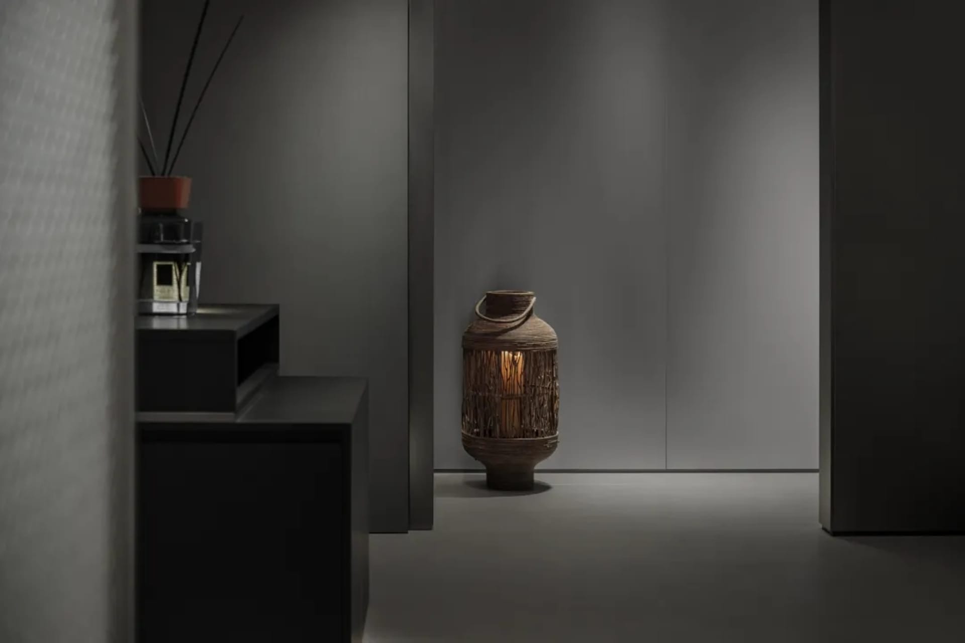 A minimalist lobby with metal furniture and a small lantern on the floor.