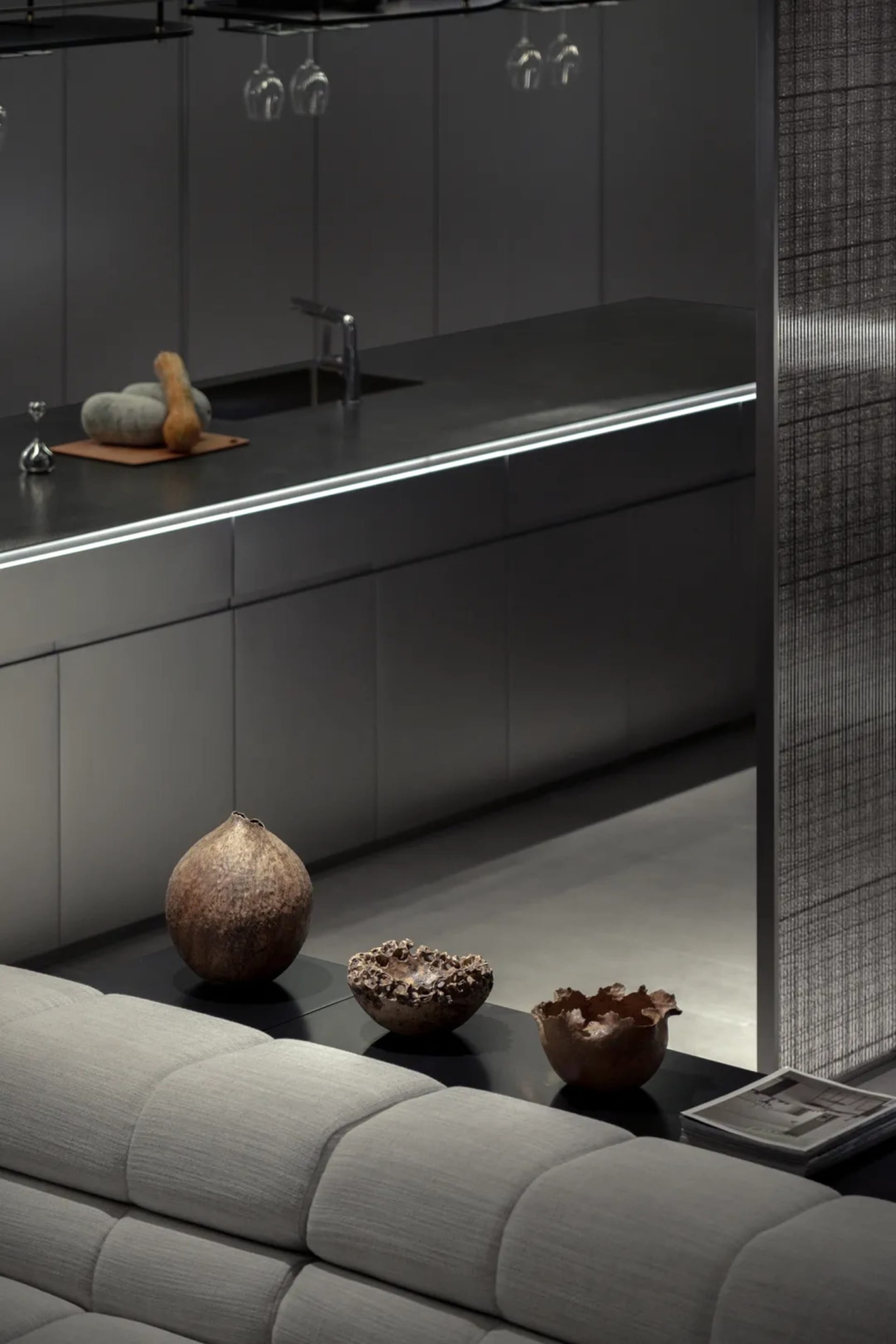 Modern, minimalist kitchen space featuring metallic-grey cabinets, concrete countertops, and metallic accessories.