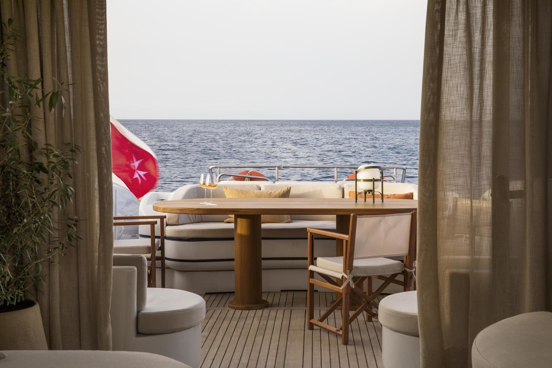 Modern yacht terrace with industrial design elements, featuring wood furniture and leather seating.