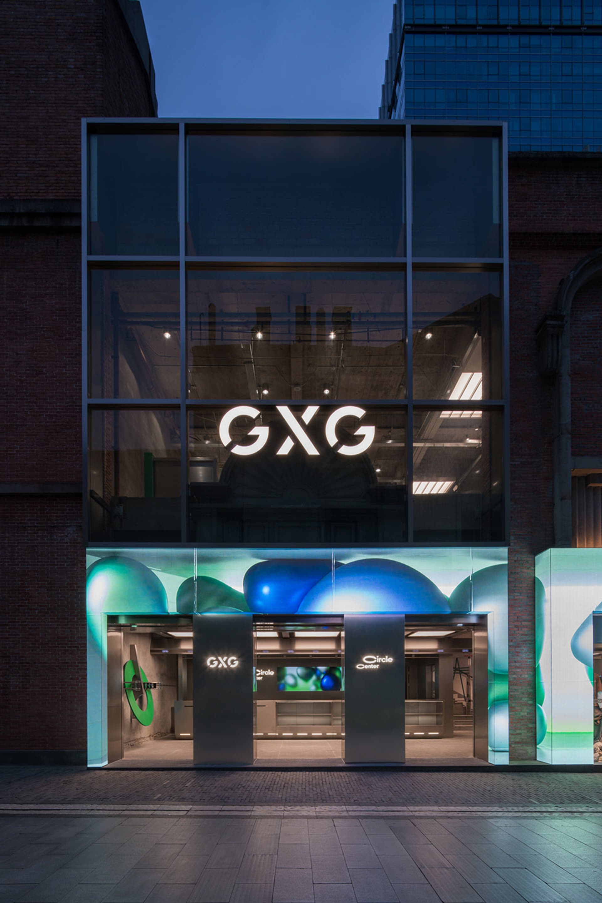夜間視角的現代零售店面，具玻璃立面與大型窗戶。