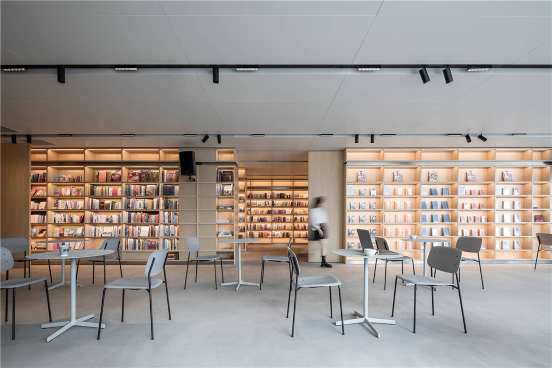 A minimalist library interior featuring neutro-wood materials and an organized shelving system.
