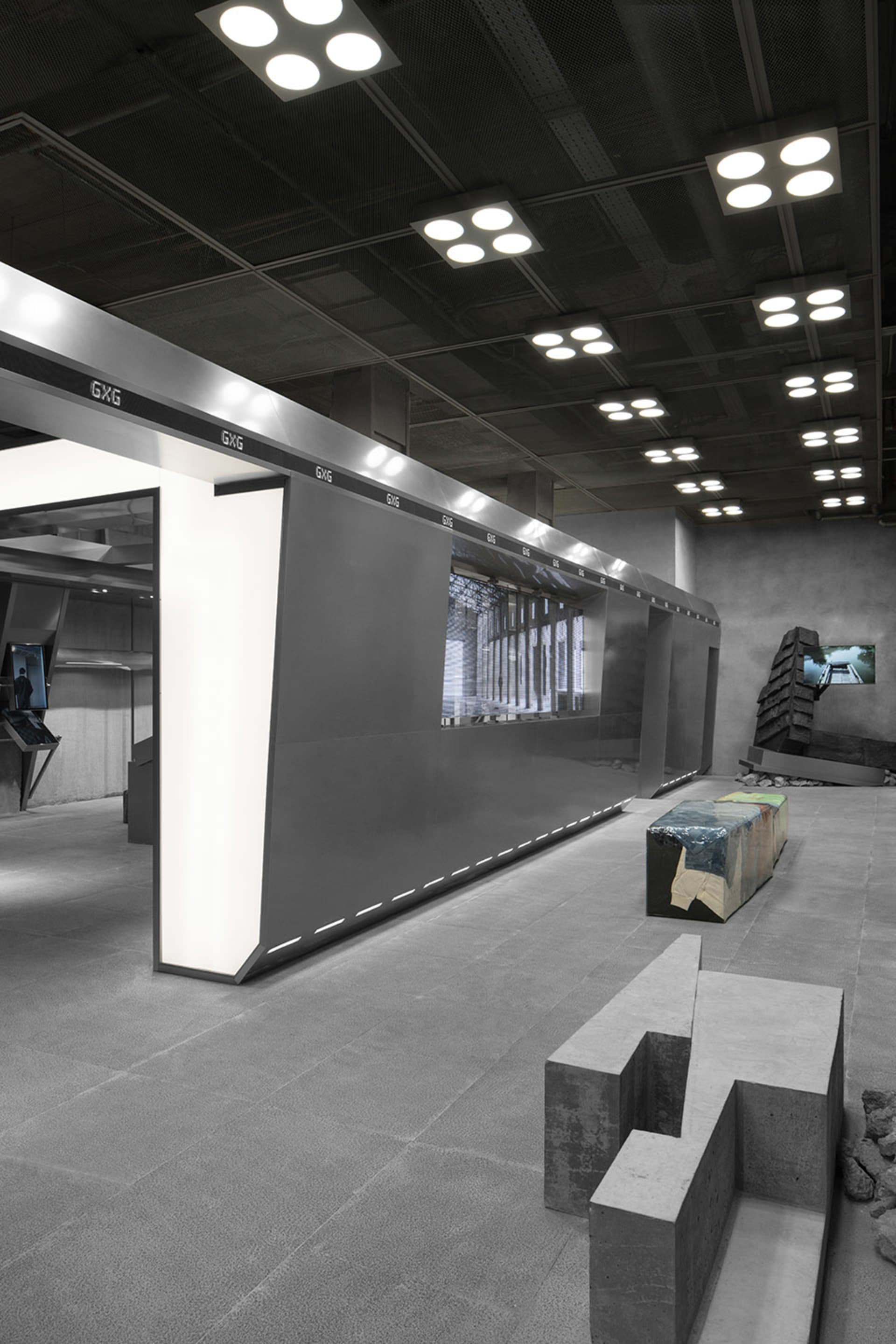 A minimalist atrium with industrial concrete walls and illuminated panels.