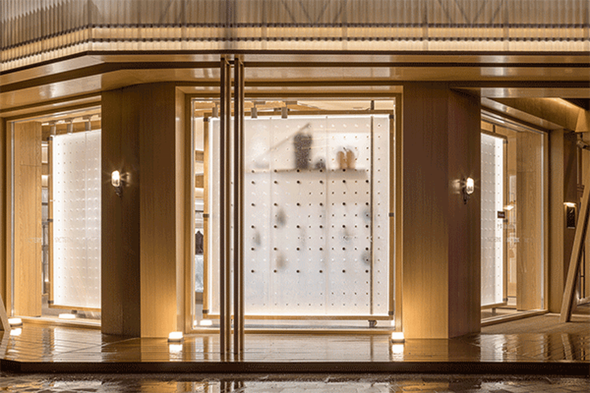 Modern storefront with glass door and white perforated paneling inside.