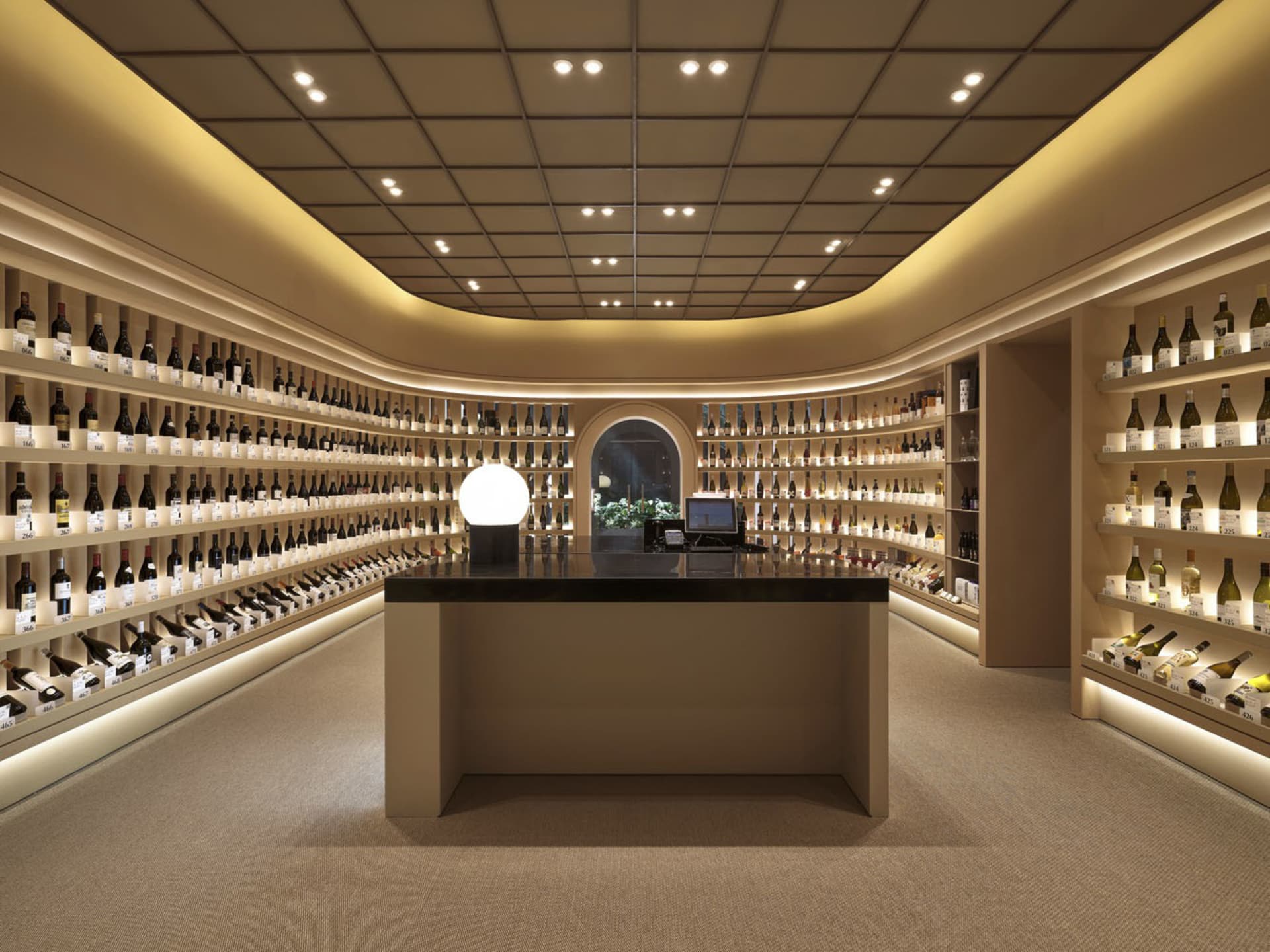 Modern wine shop interior with wooden finishes and extensive wine bottle display.