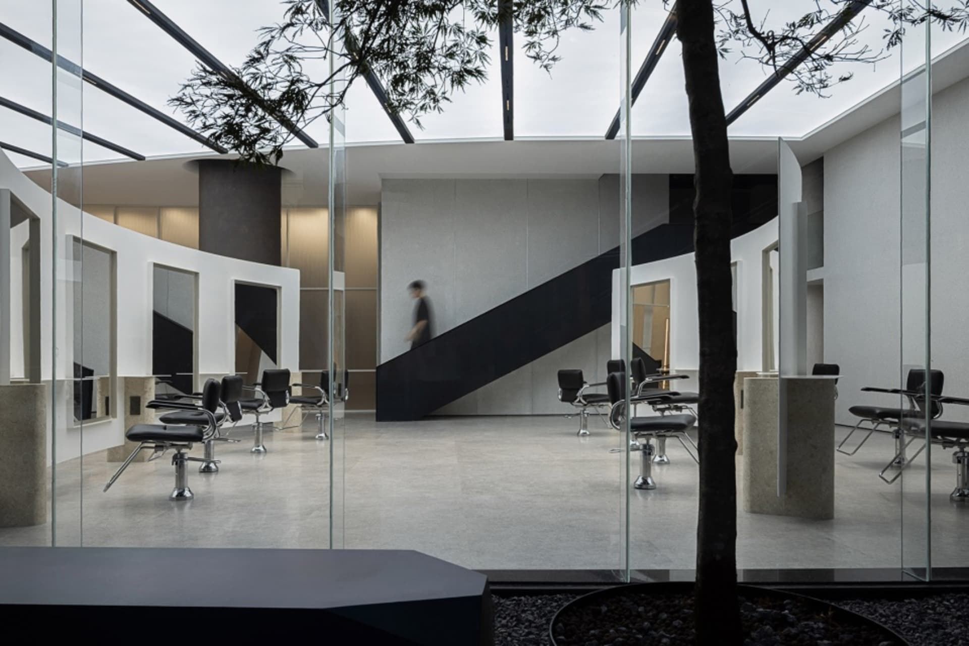 A sleek, modern salon interior with black and white color scheme, glass walls, and metal chairs.