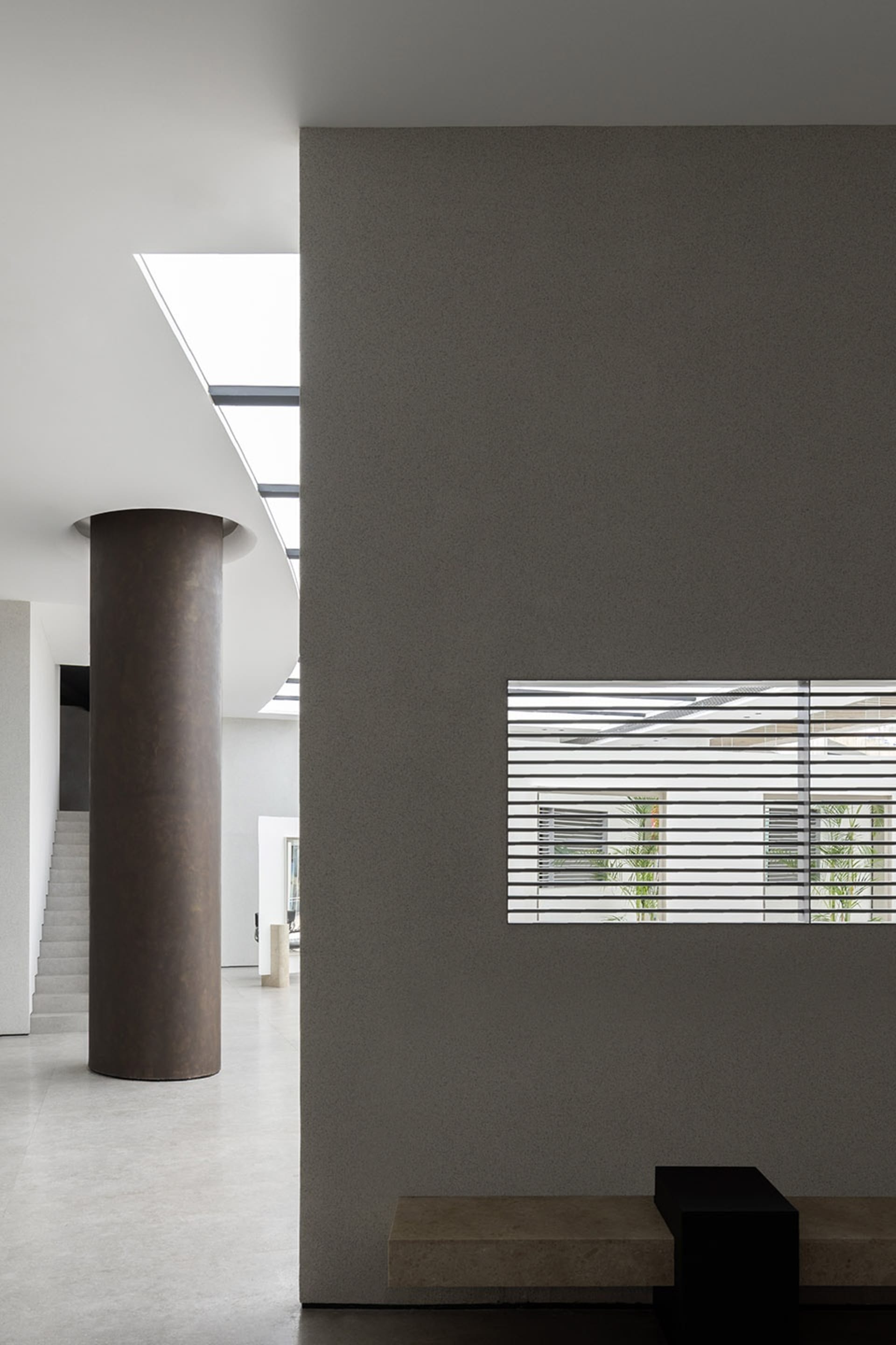 A modern interior design featuring concrete walls and a large skylight.