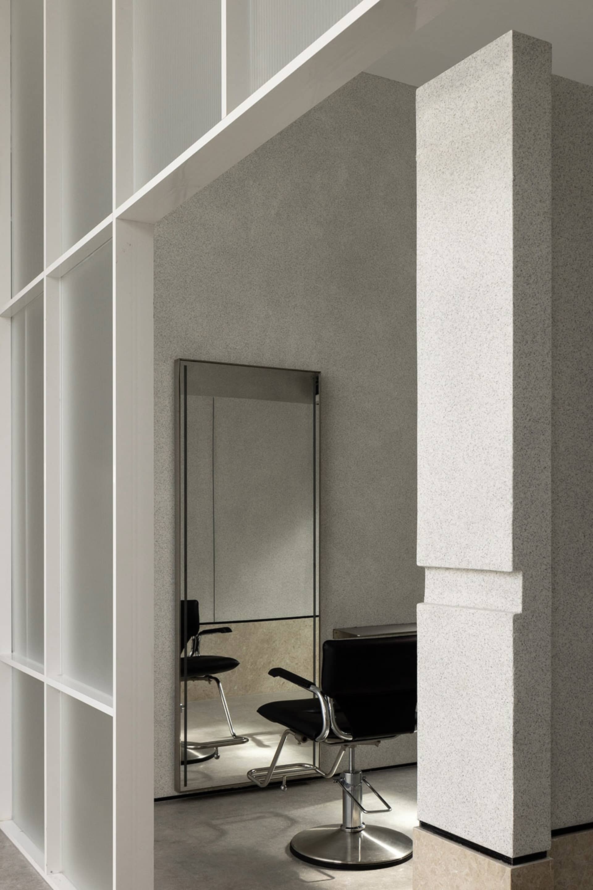 Modern minimalist salon featuring metallic furniture and large mirrors.