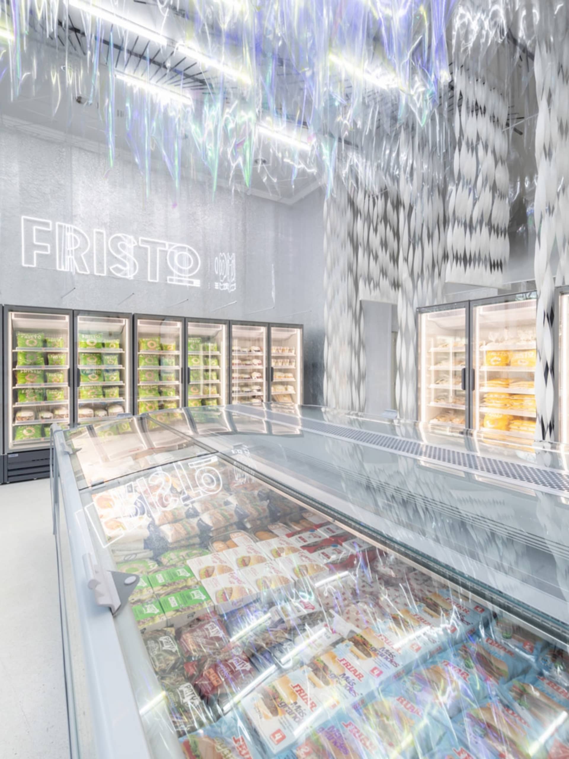 A modern supermarket with metallic and glass elements and illuminated signage.