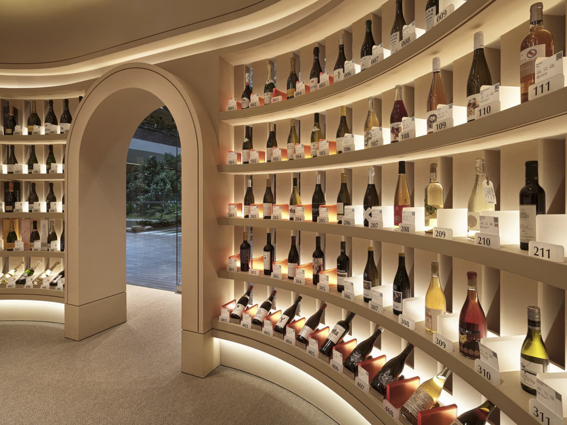 A well-lit interior space featuring a curved wall dedicated to displaying bottles of wine.