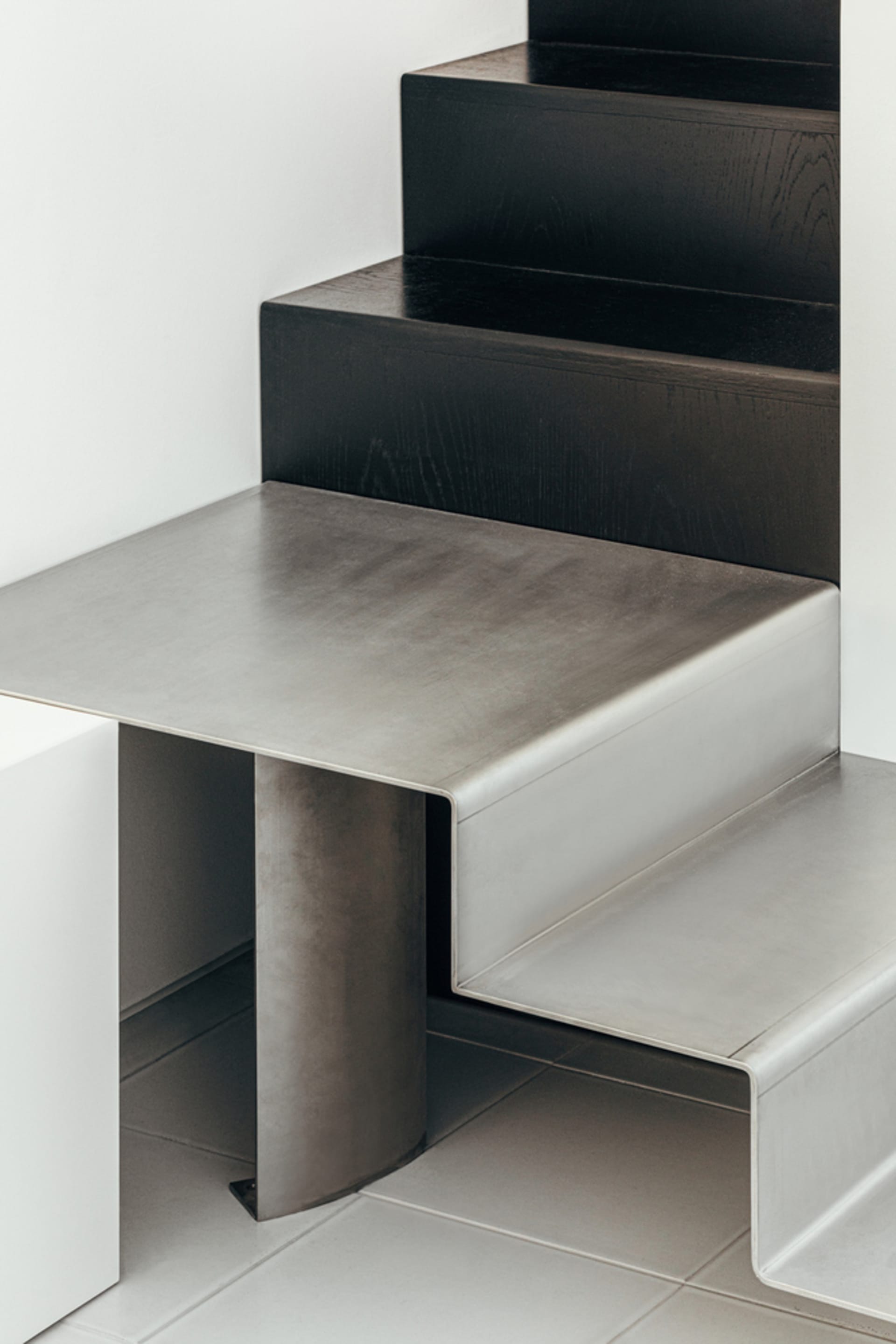 Modern, minimalist interior design featuring a sleek, metallic staircase with wooden steps.