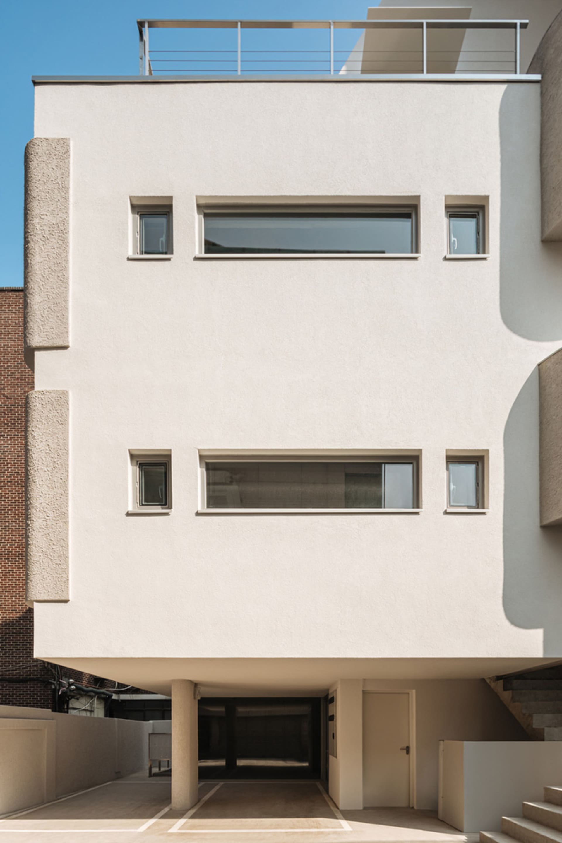 一座現代建築物,擁有混凝土外牆、大型窗戶與屋頂陽台。