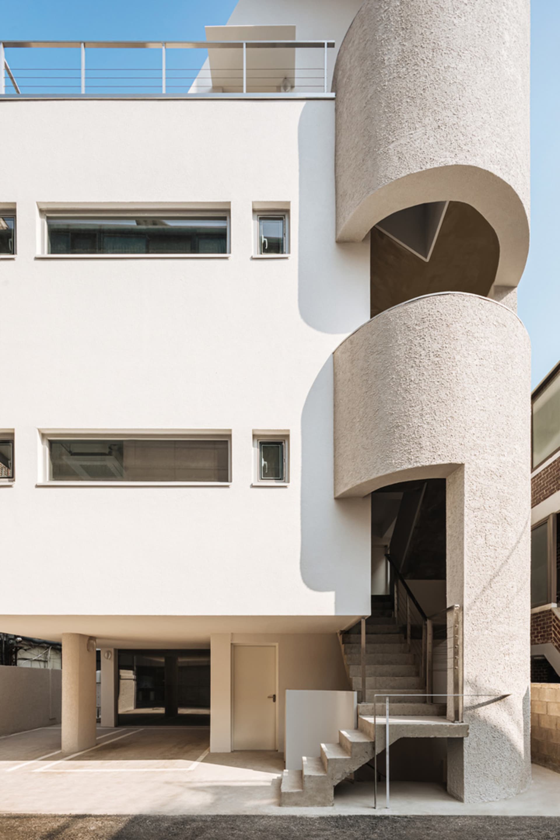A modern building with a curved concrete exterior and a spiral staircase.