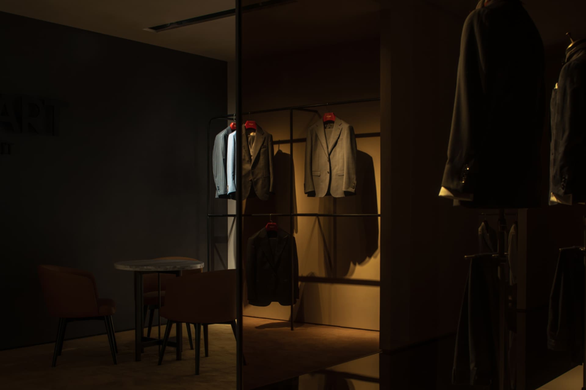 服飾店展示區，衣架上懸掛著西裝，搭配簡約設計元素。