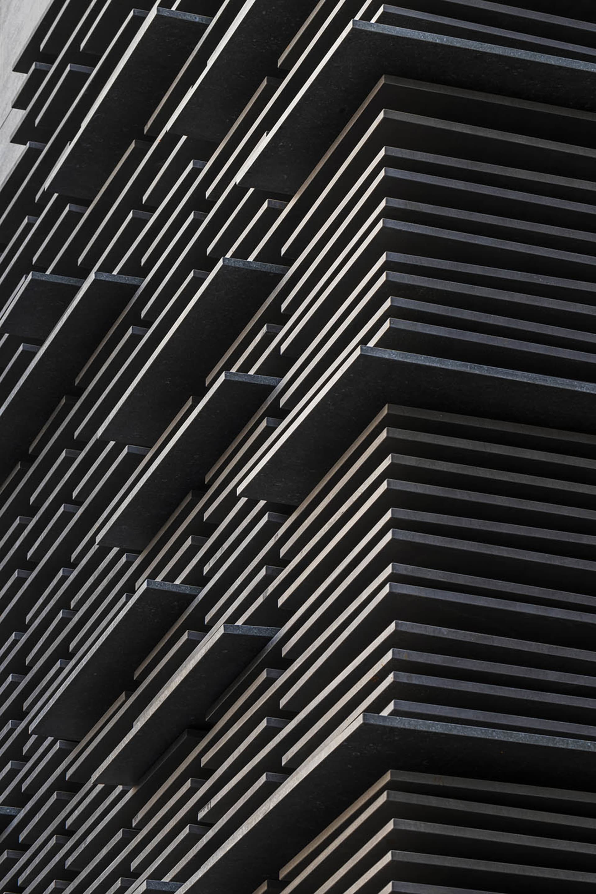 A close-up view of a modern building facade with black metallic panels.