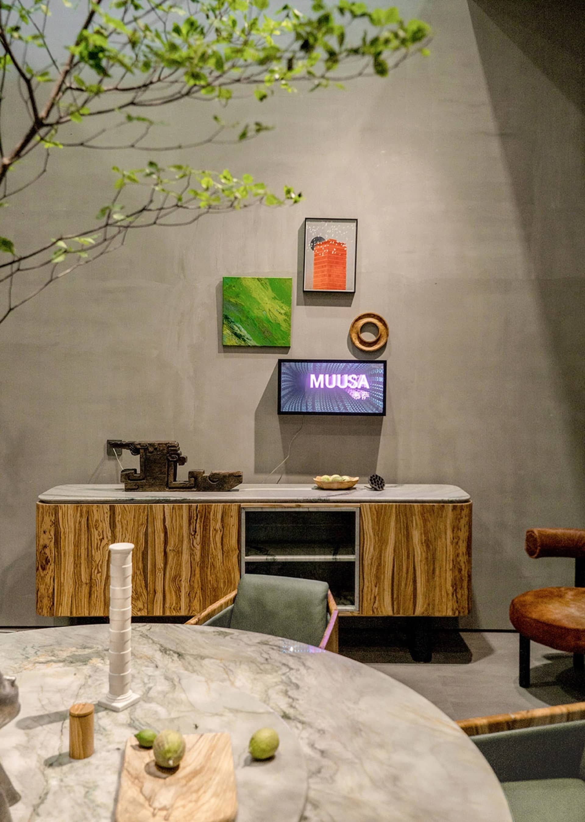 Modern dining room with wood and concrete furniture, green plants, and minimalist decor.