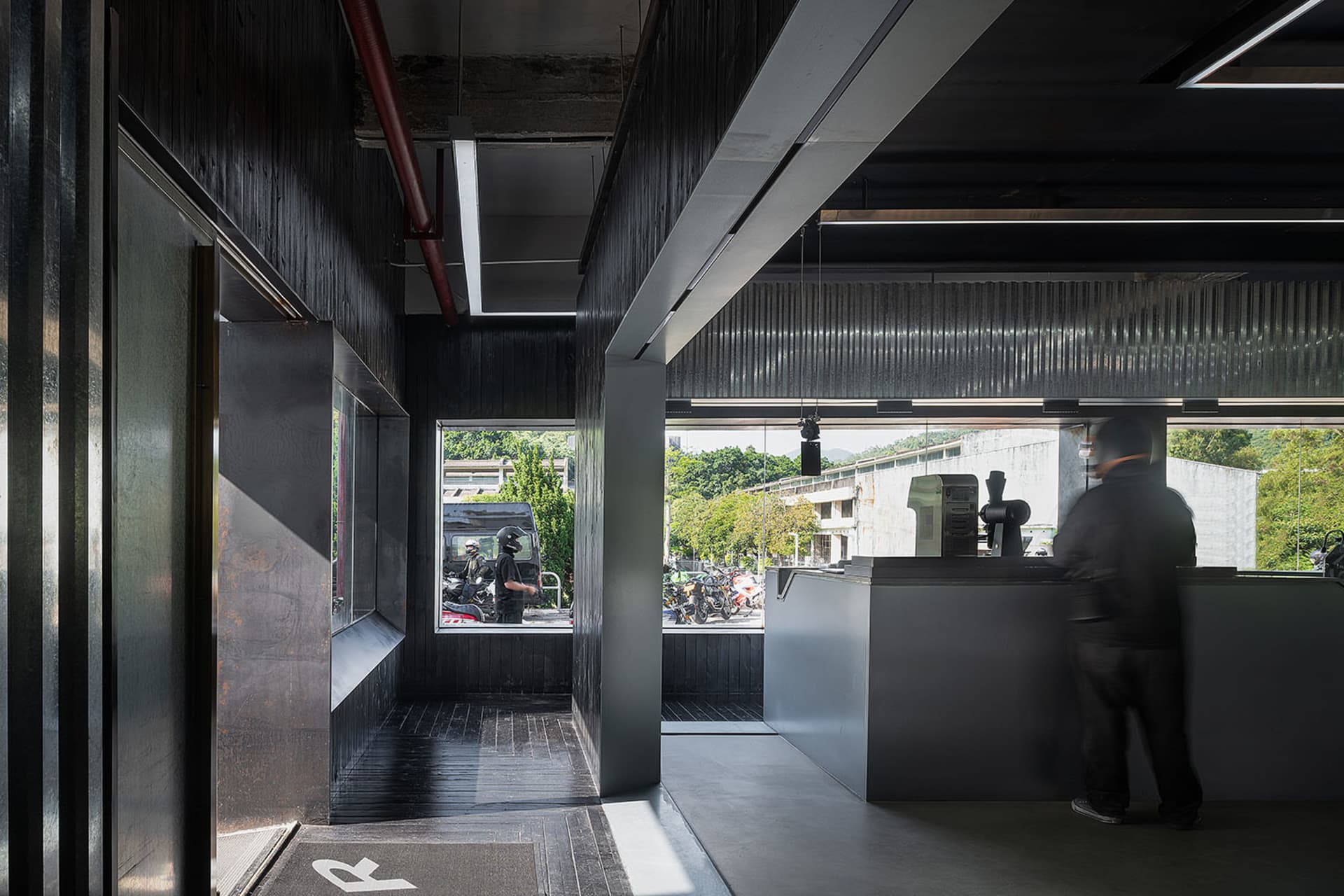 A person wearing a helmet stands at a dark wood coffee shop counter.