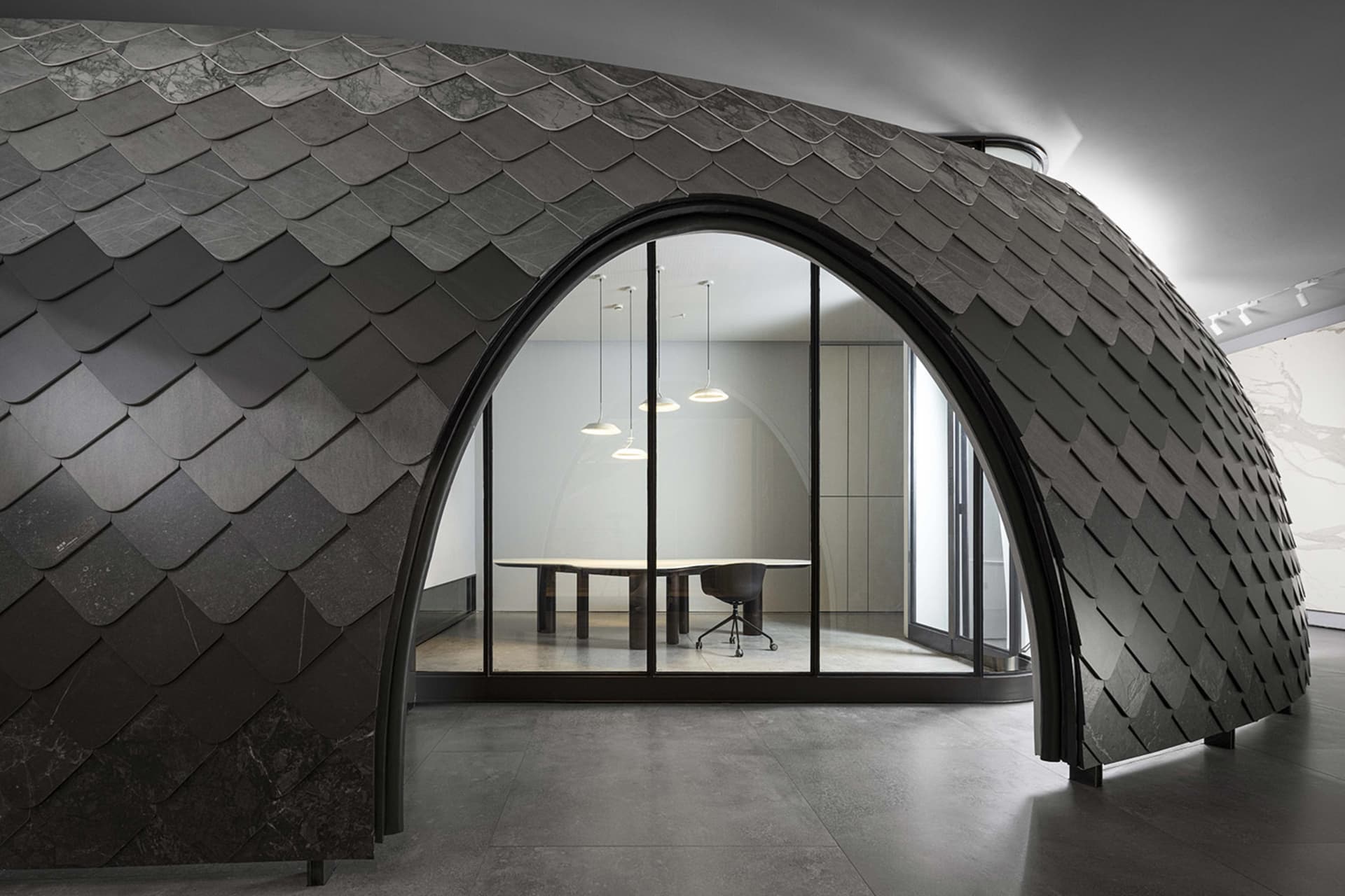 Modern office interior featuring metallic scalloped wall with arched doorway leading to a conference room with sleek design