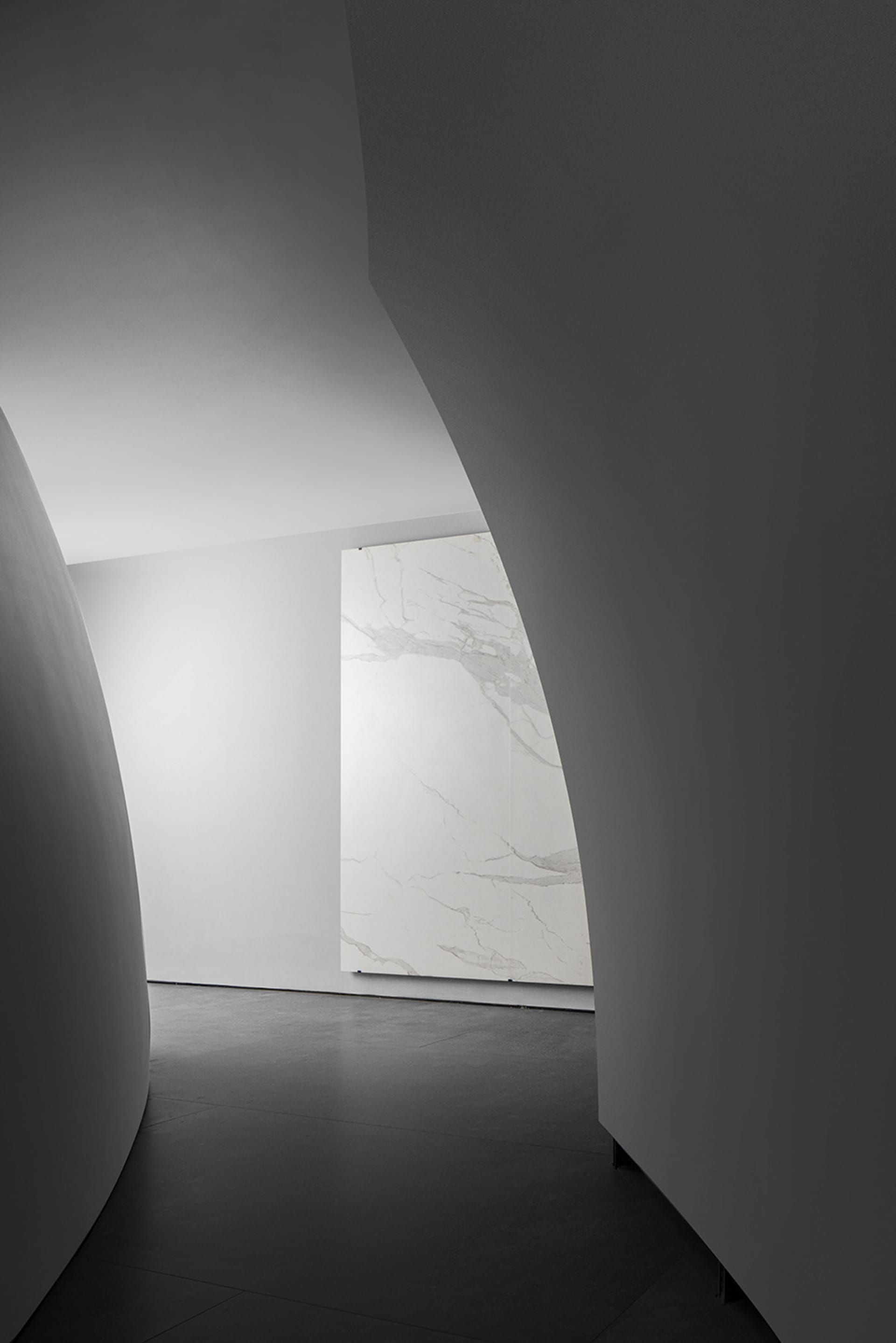 A modern minimalist interior featuring white marble accents and curved walls.