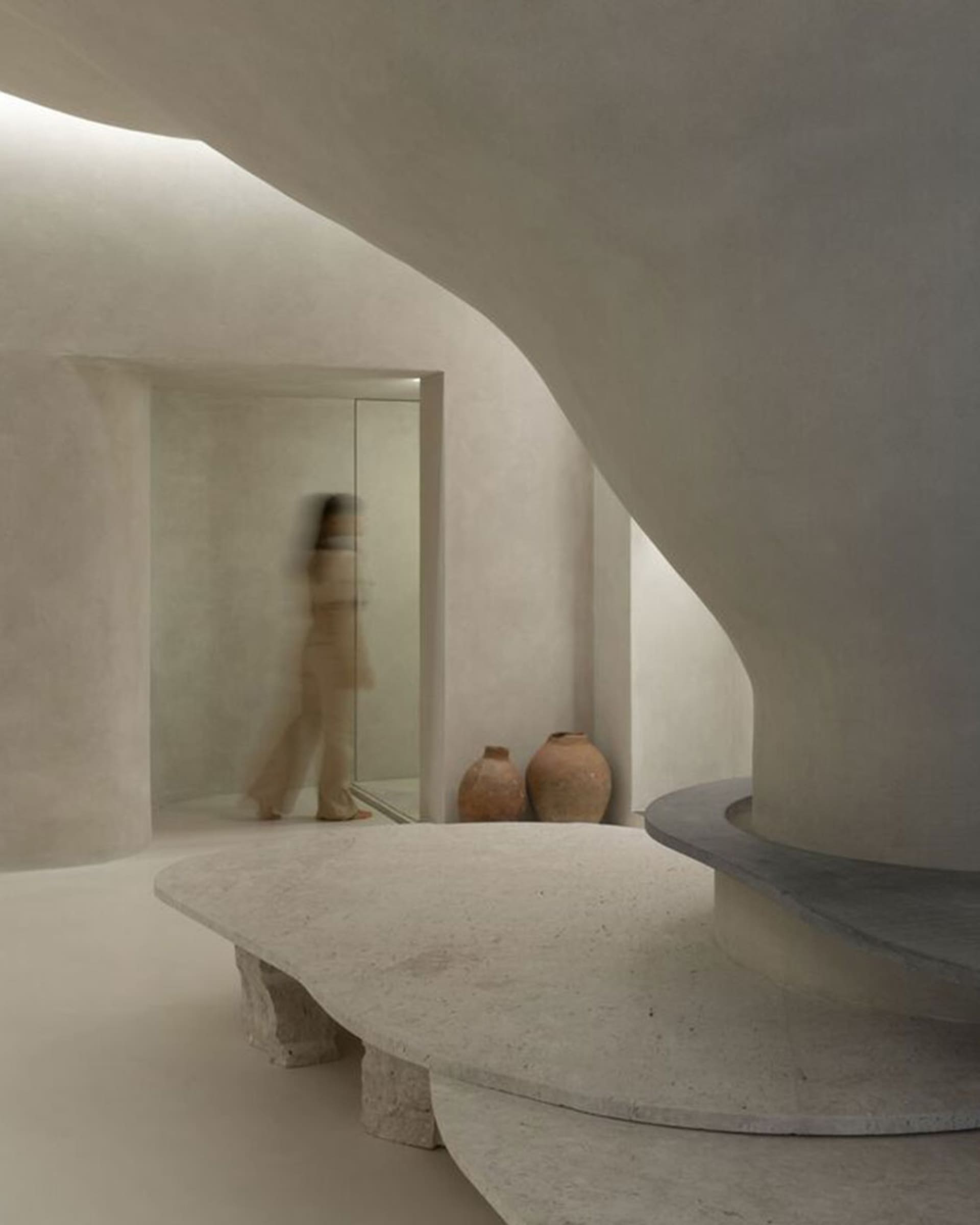 A minimalist, abstract concrete space with smooth, curved surfaces and earthy tones.