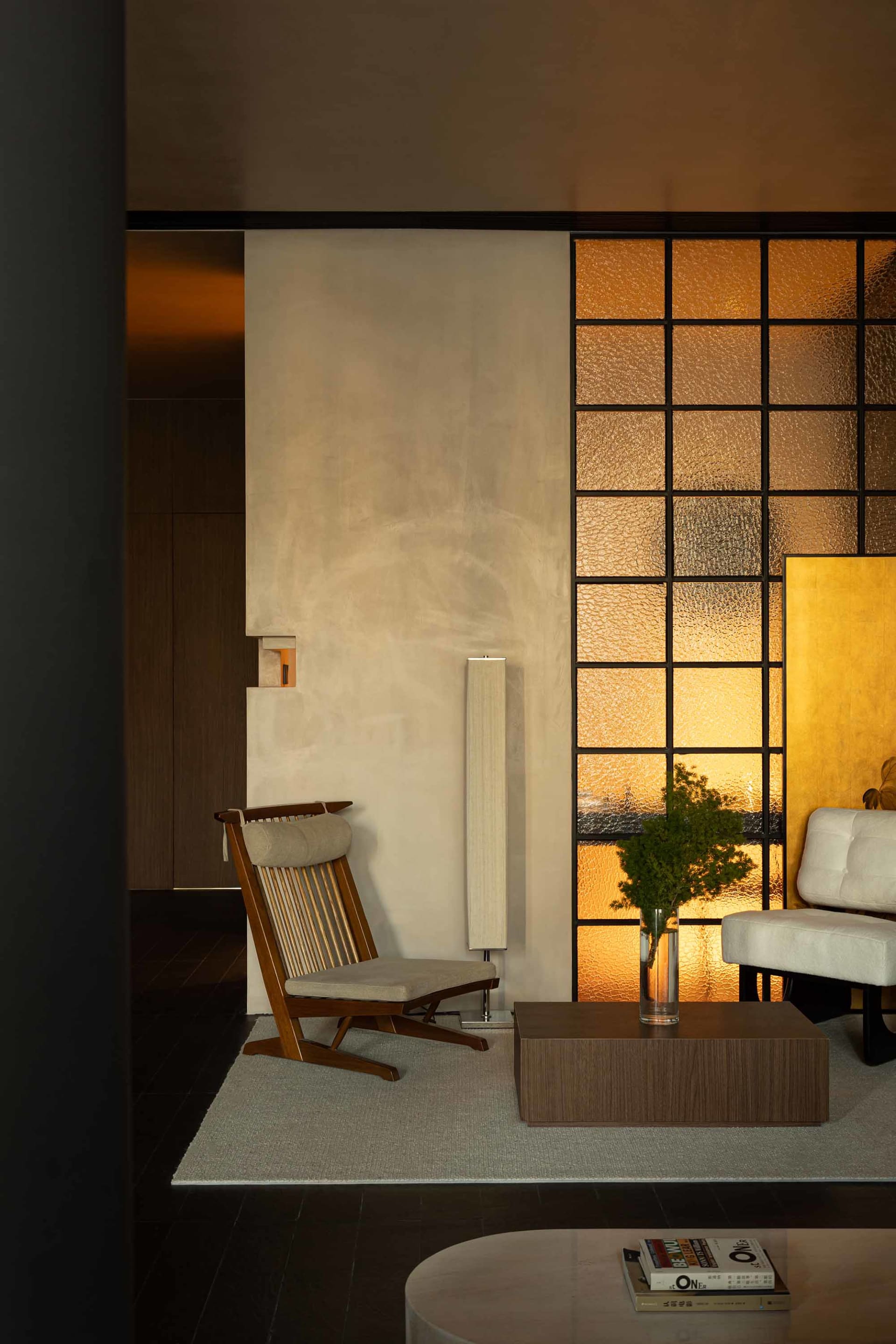 A minimalist living room featuring a glass window with a textured surface, a wooden chair, a wooden coffee table, and a white