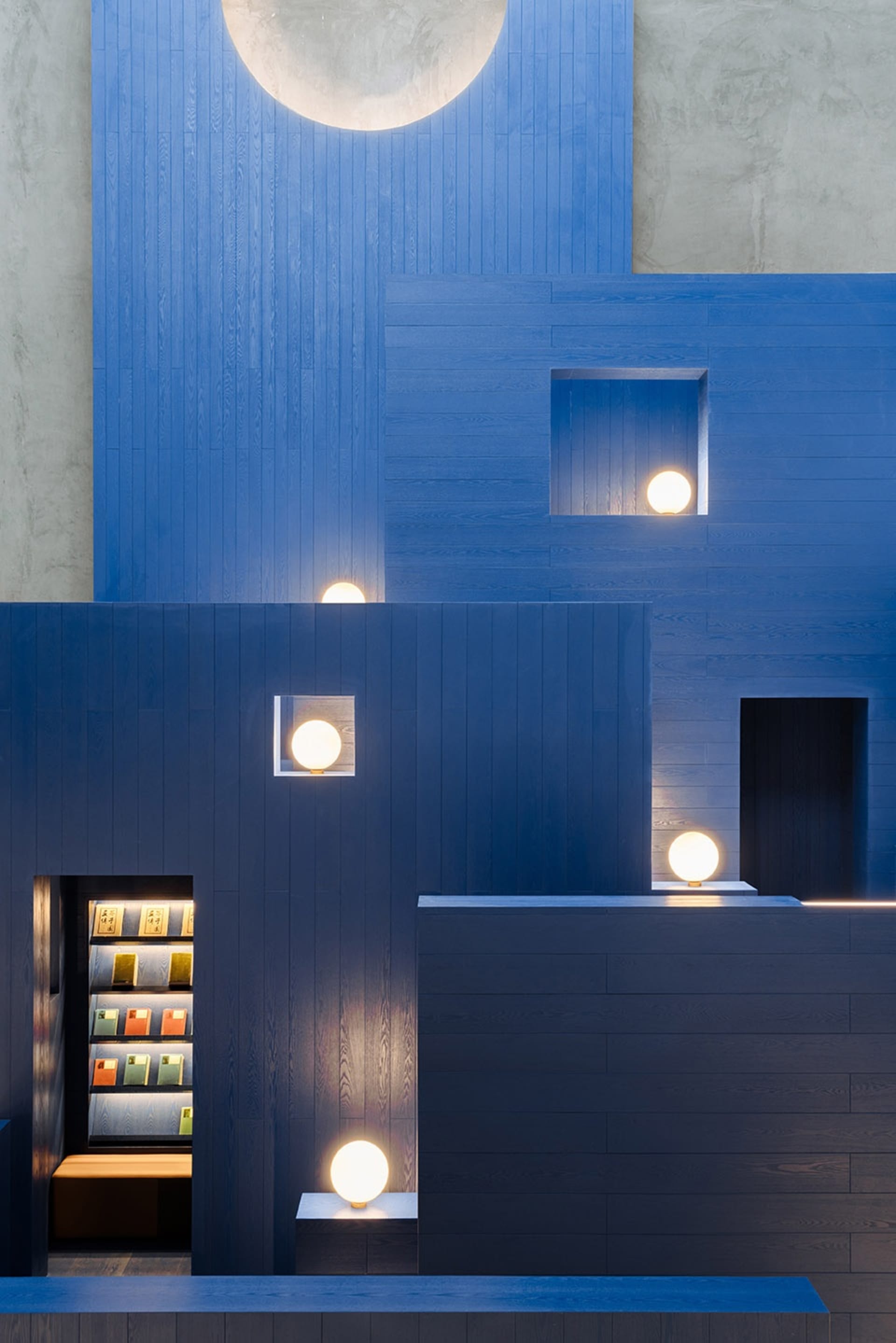 A minimalist retail shelf with books illuminated by spherical lights.