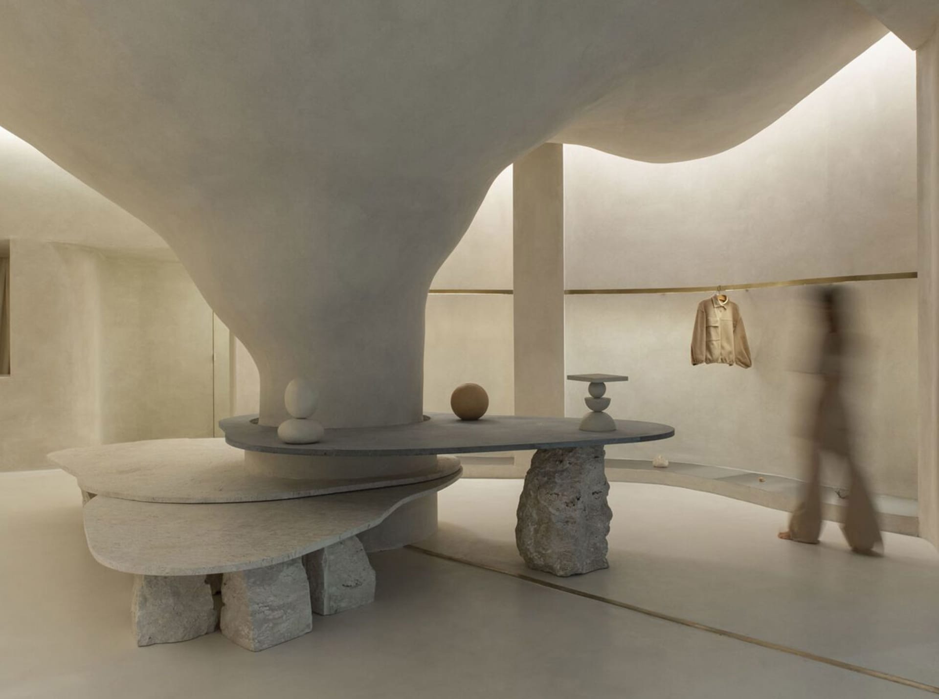 Minimalist retail space featuring a modern concrete countertop and abstract sculptures.
