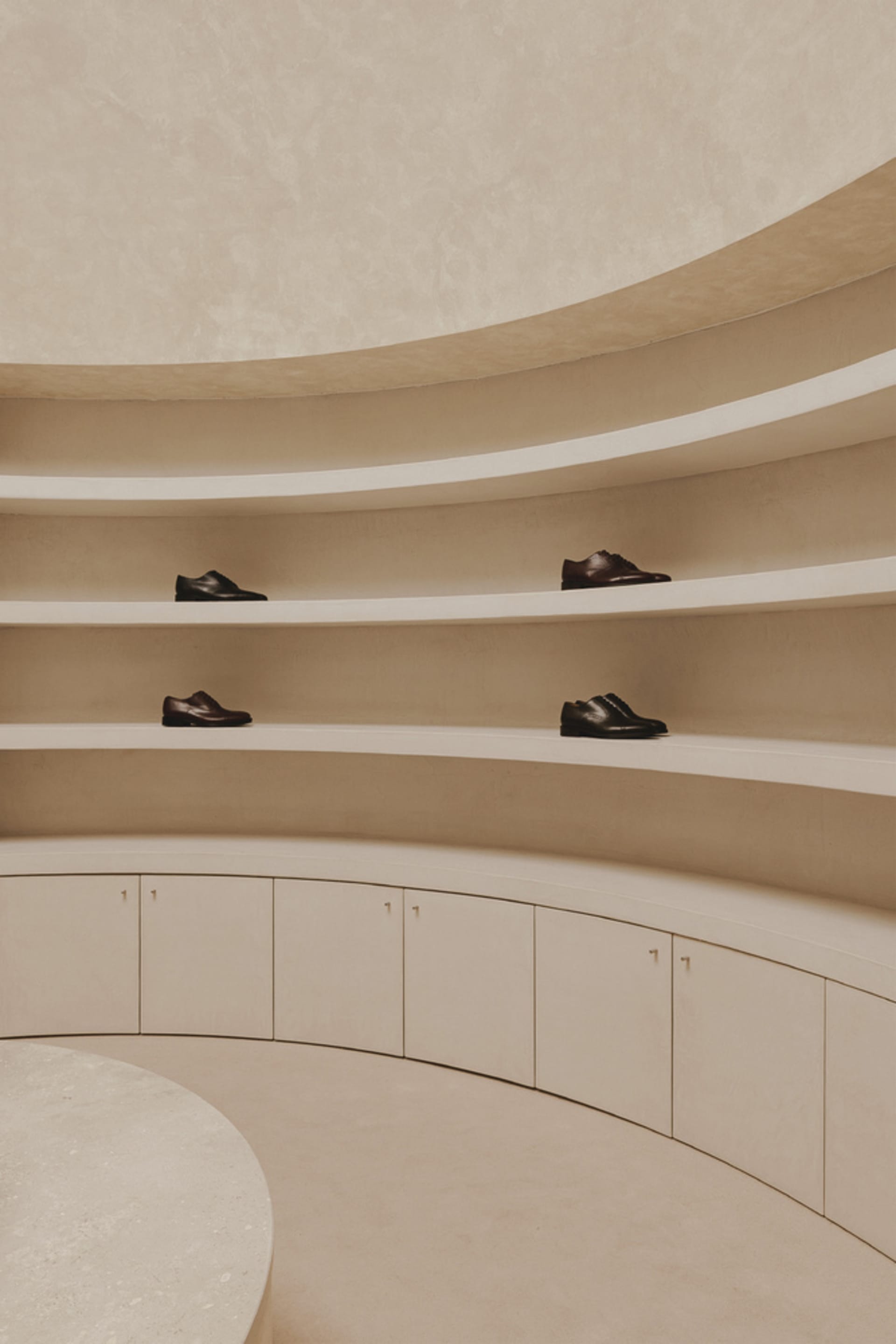 A modern room with a shoe collection displayed on shelves and cabinets made of concrete.