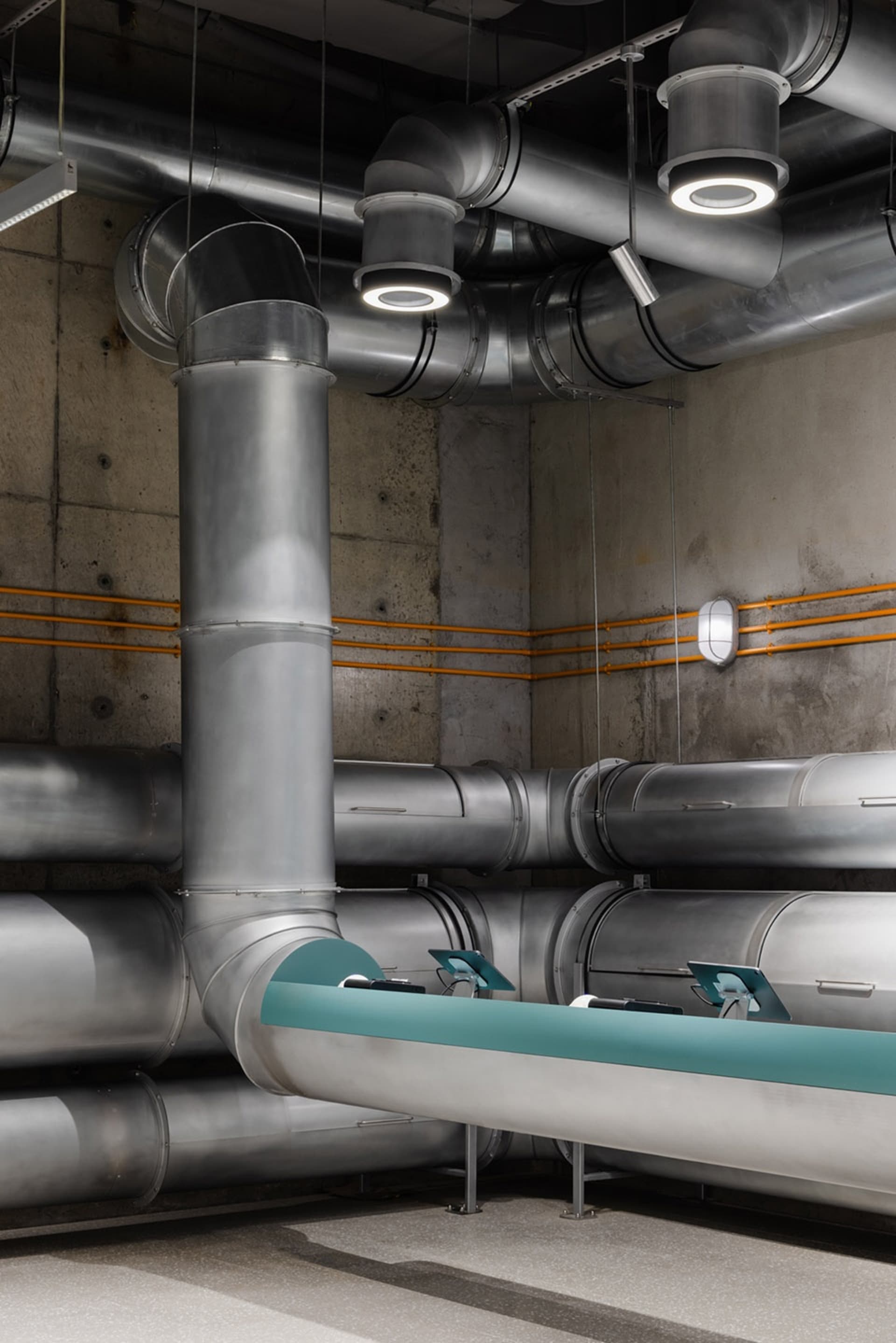 An industrial building interior featuring exposed metal pipes and concrete walls.