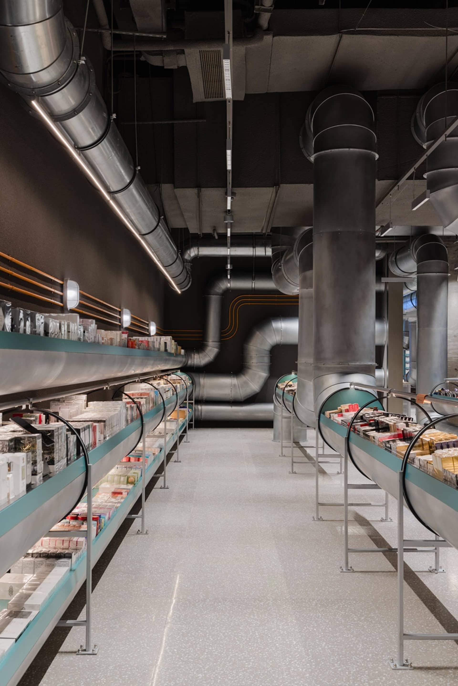 Industrial-style retail store with concrete flooring, metal shelving, and glass pipes.
