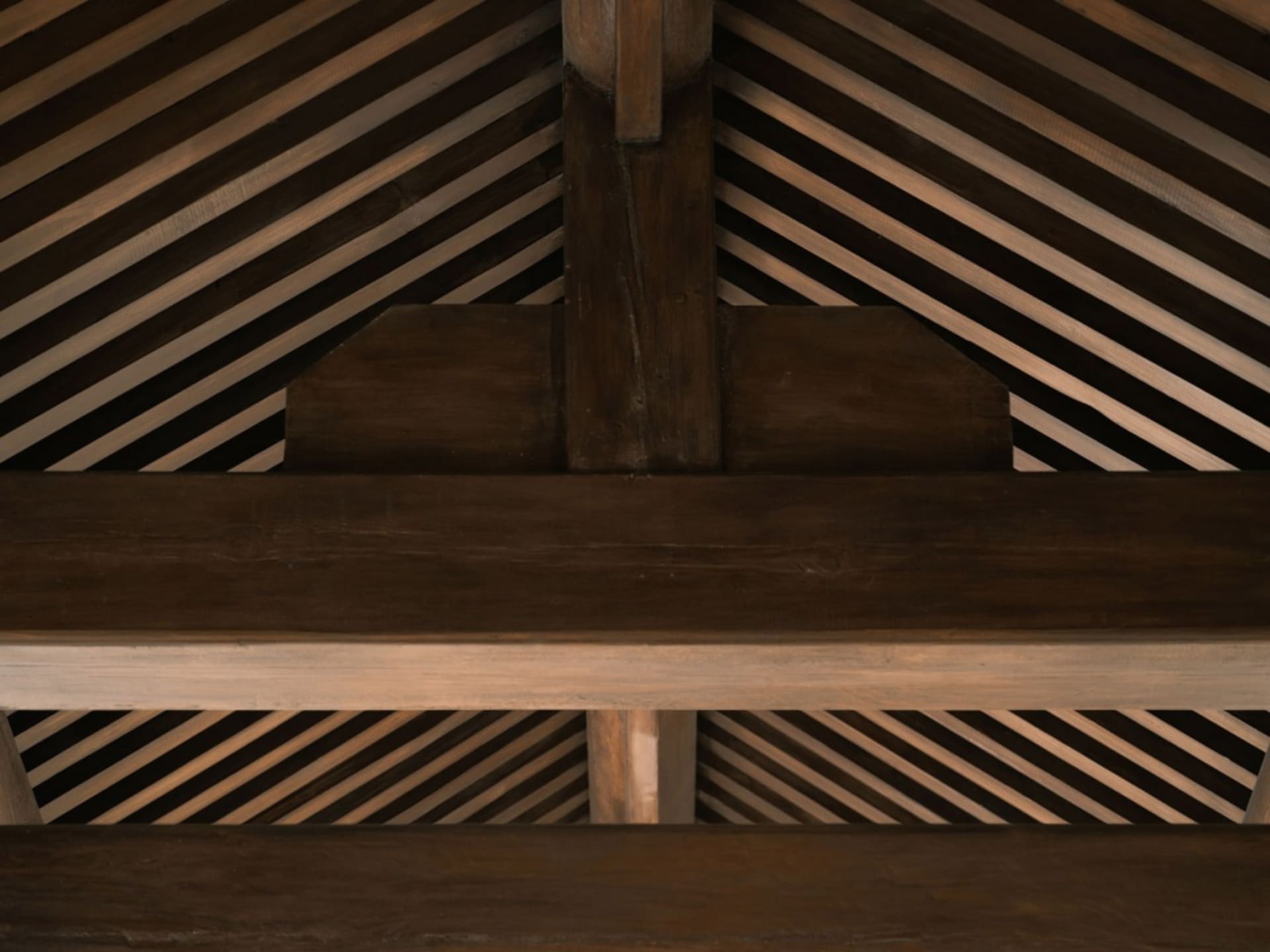A close-up of a wooden roof structure showing intersecting beams and beams.