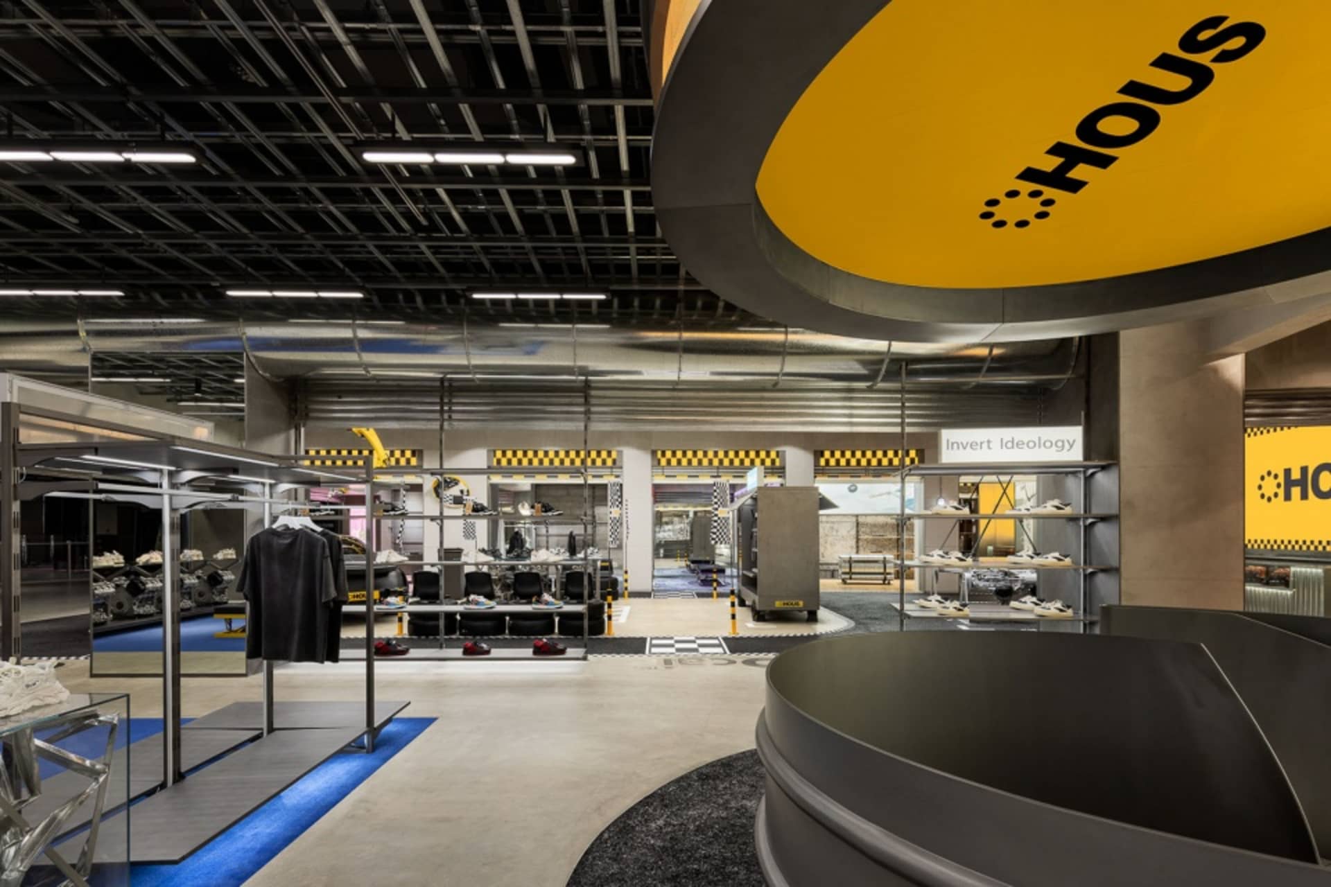 A modern fashion retail store with metallic finishes, concrete flooring, and glass displays.