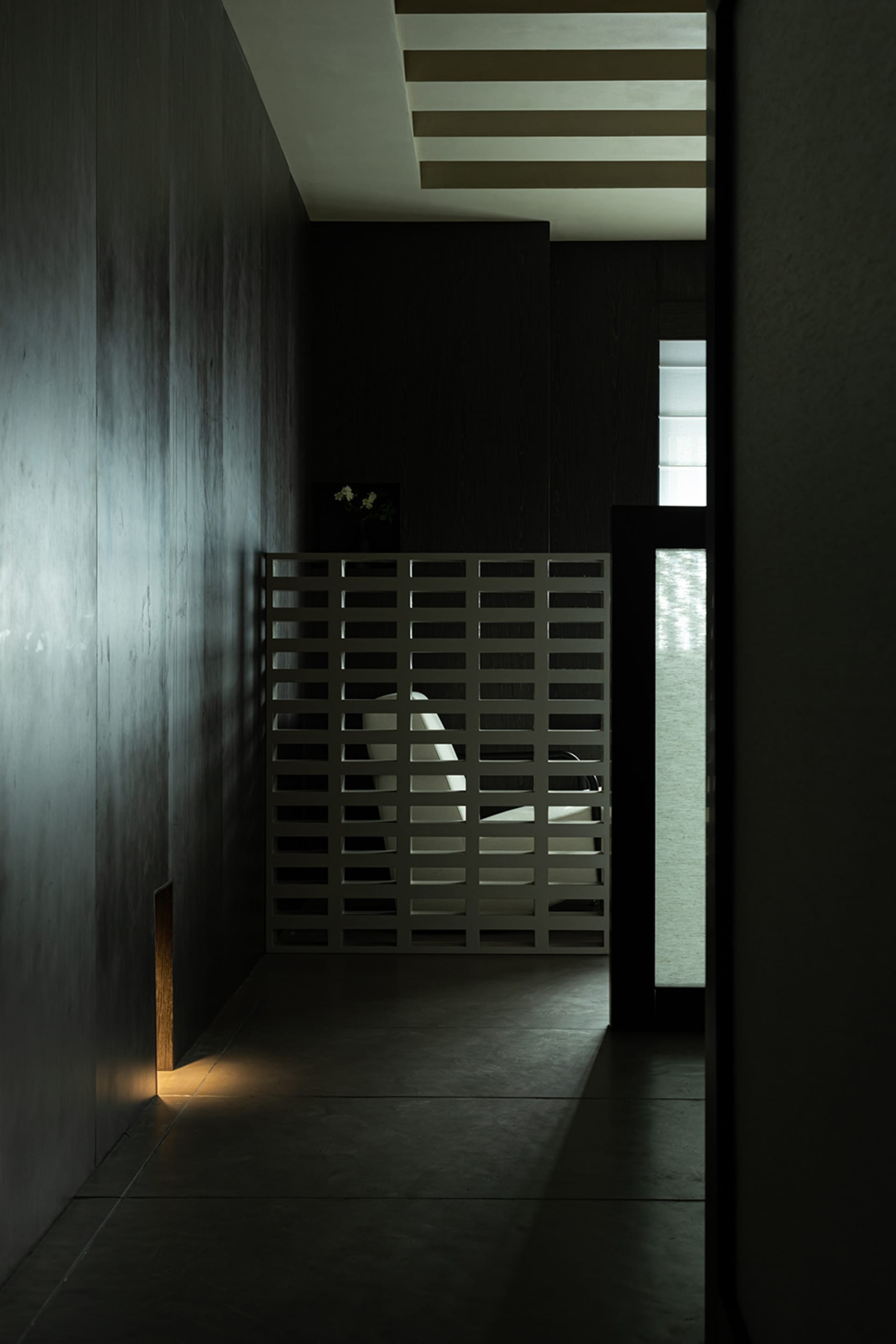 A minimalist interior design featuring a glass wall panel, with light filtering through