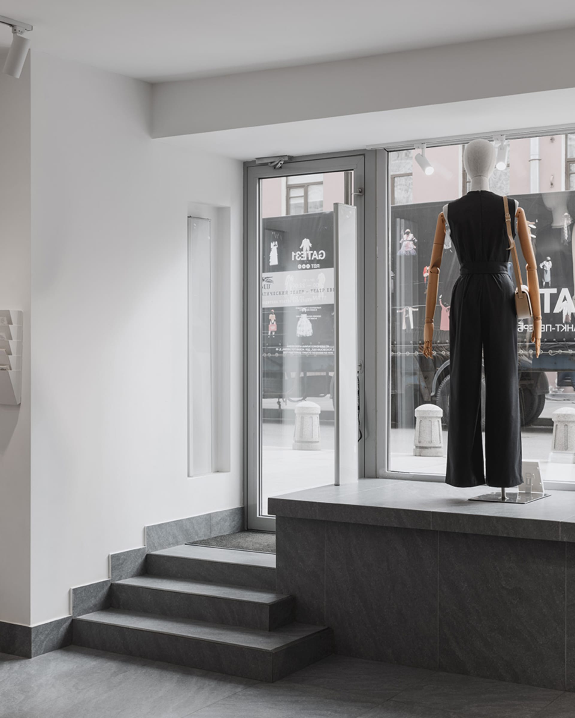 Modern retail storefront with concrete walls and a display featuring a mannequin.
