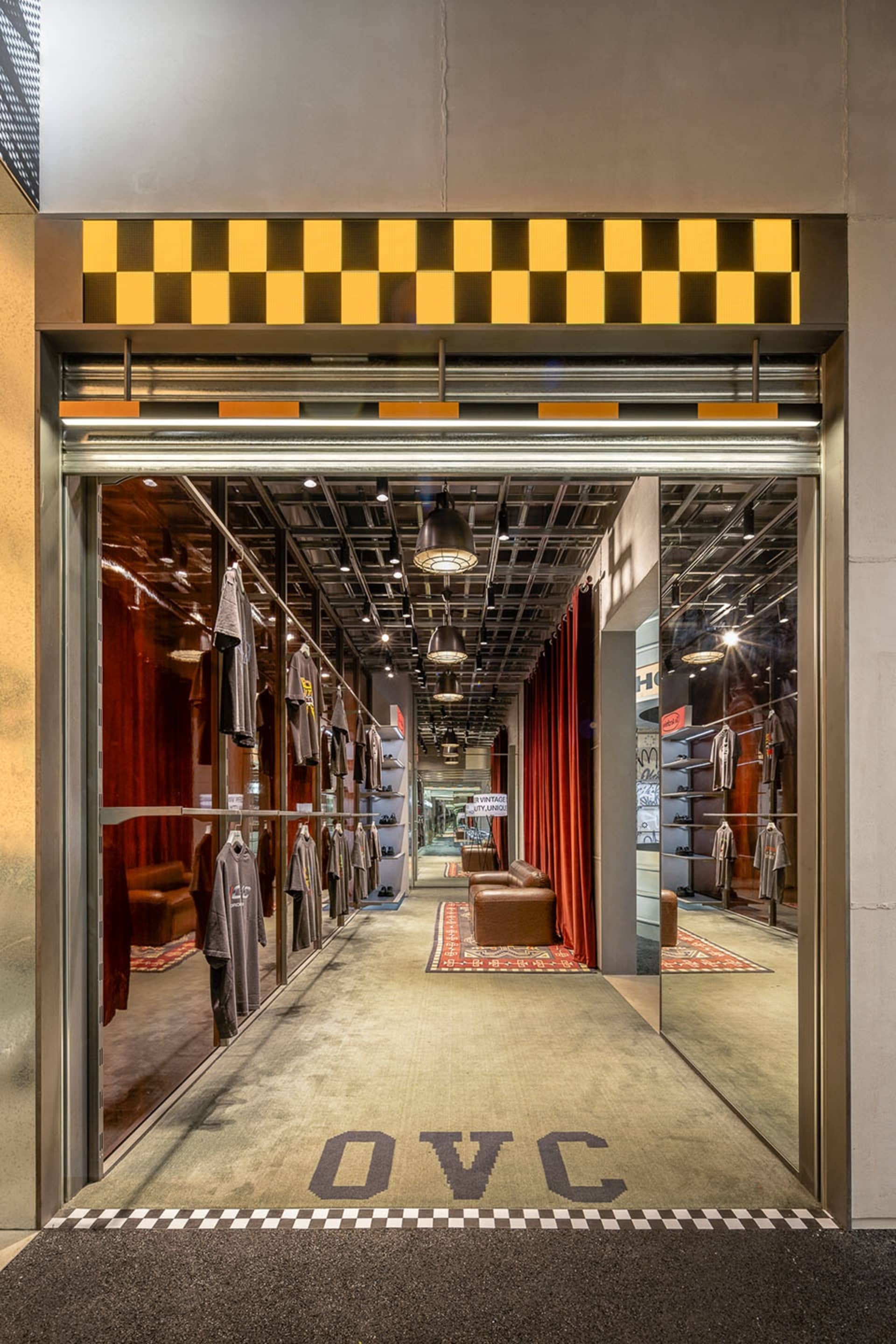 工業風服飾店室內空間,混凝土地板與牆面,衣物陳列於衣架上。