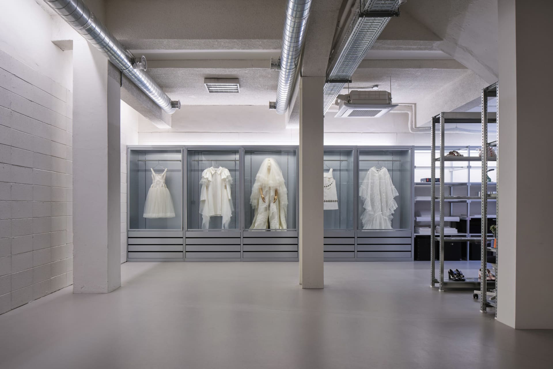 Modern retail clothing store with glass display cases showcasing white garments.