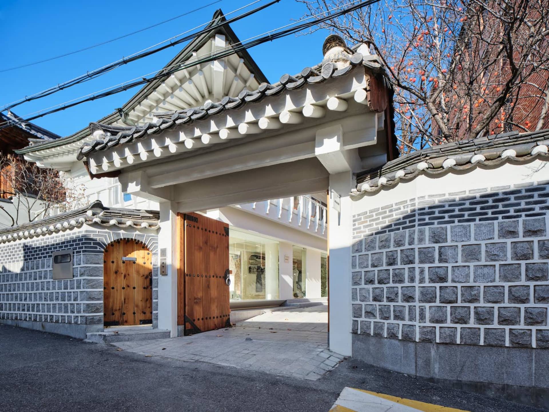 A traditional South Korean building facade featuring a stone wall and wooden arched doorway.